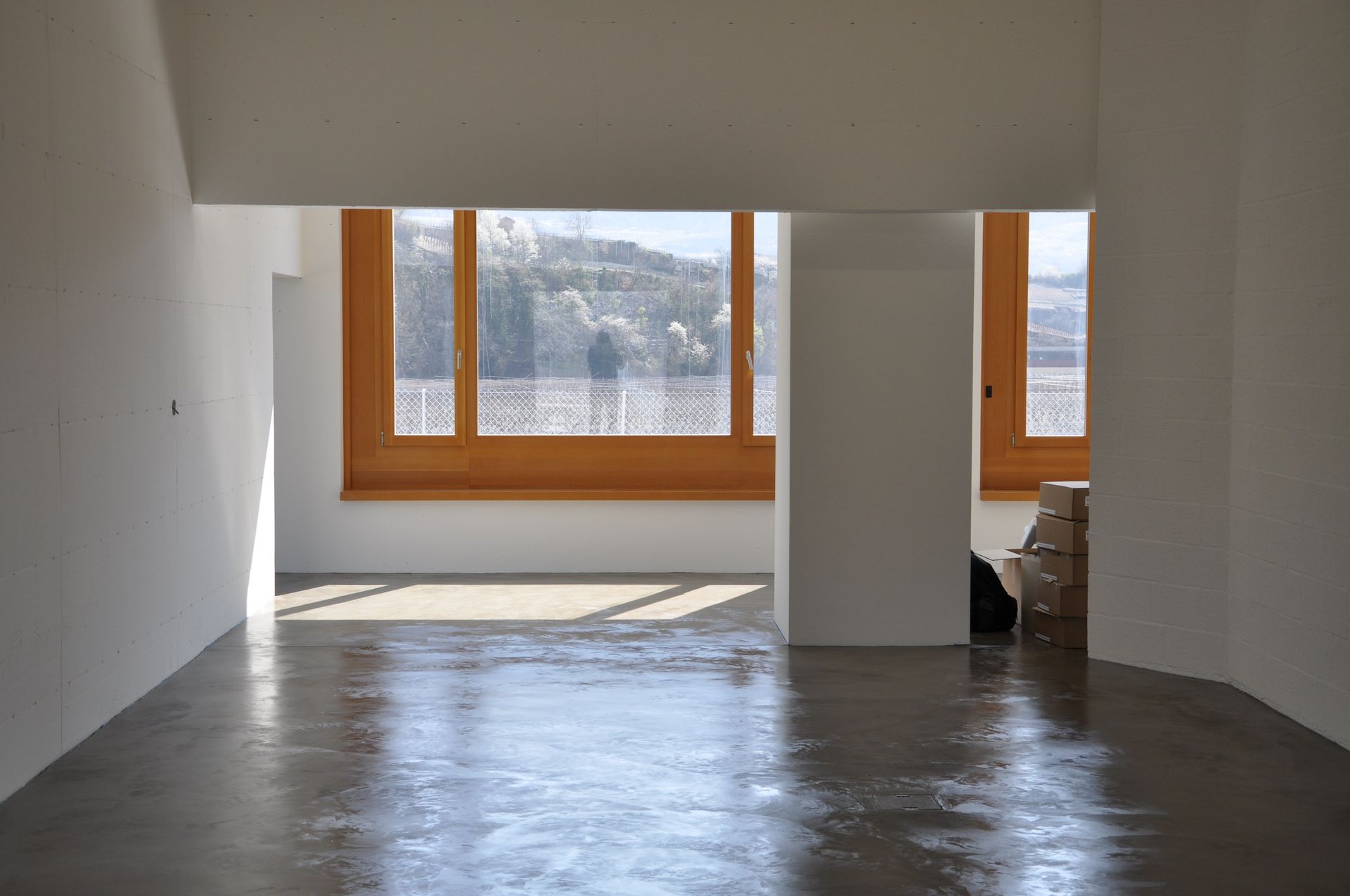 Une grande pièce vide avec beaucoup de fenêtres et de boîtes sur le sol.