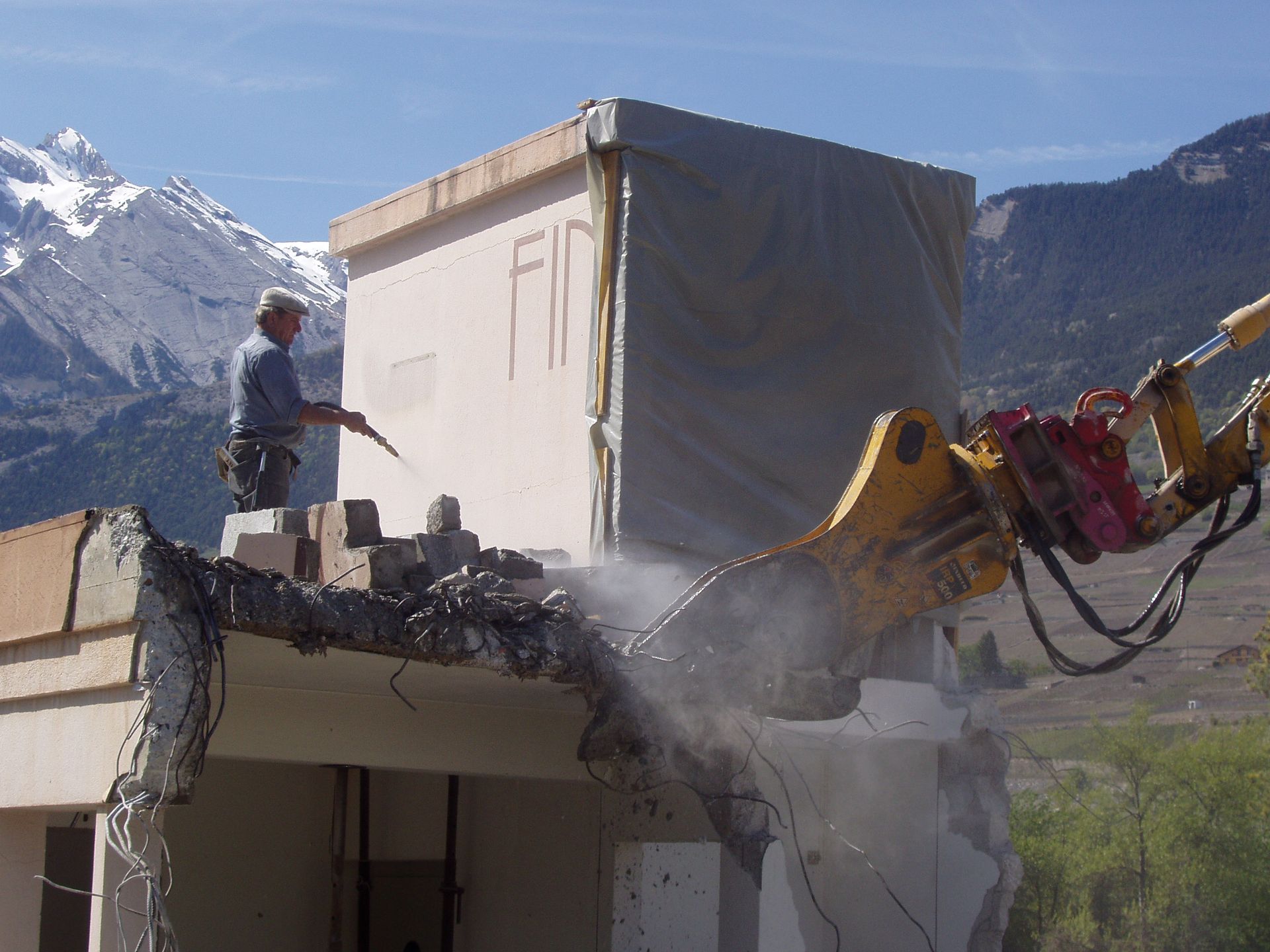 Un homme se tient au sommet d'un bâtiment en train d'être démoli.