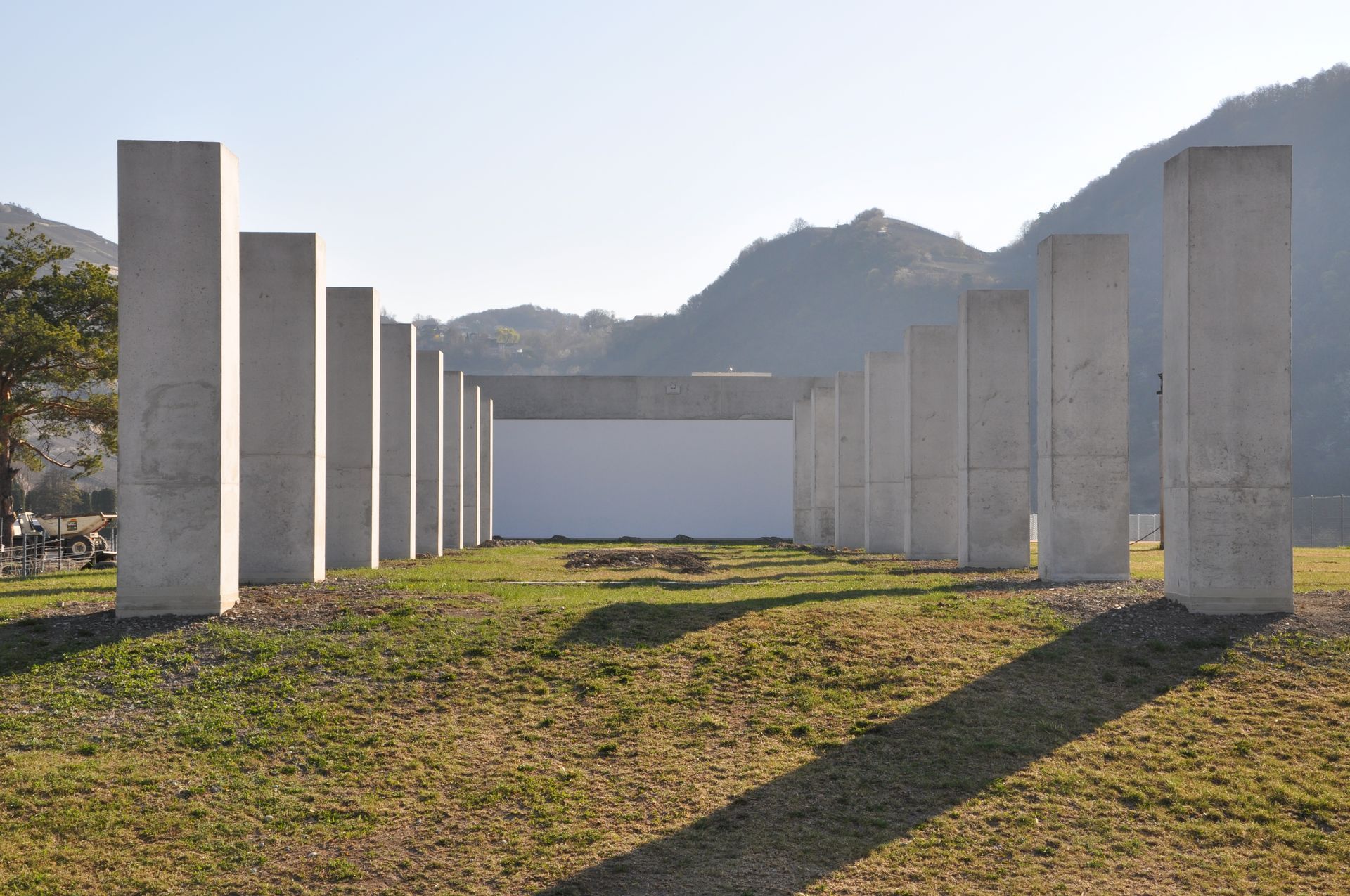 Une rangée de piliers en béton dans un champ avec des montagnes en arrière-plan