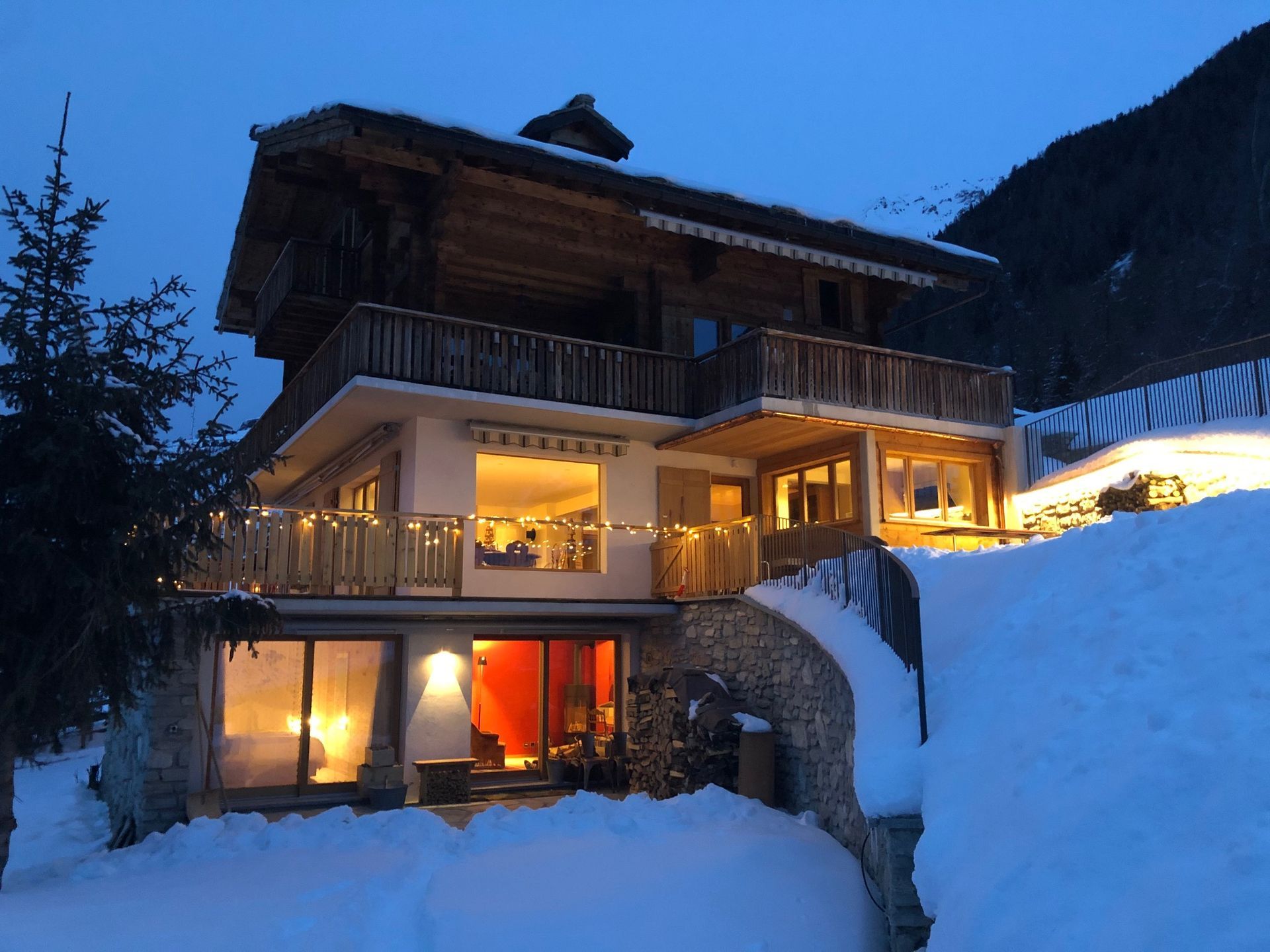 Une grande maison est entourée de neige et est illuminée la nuit