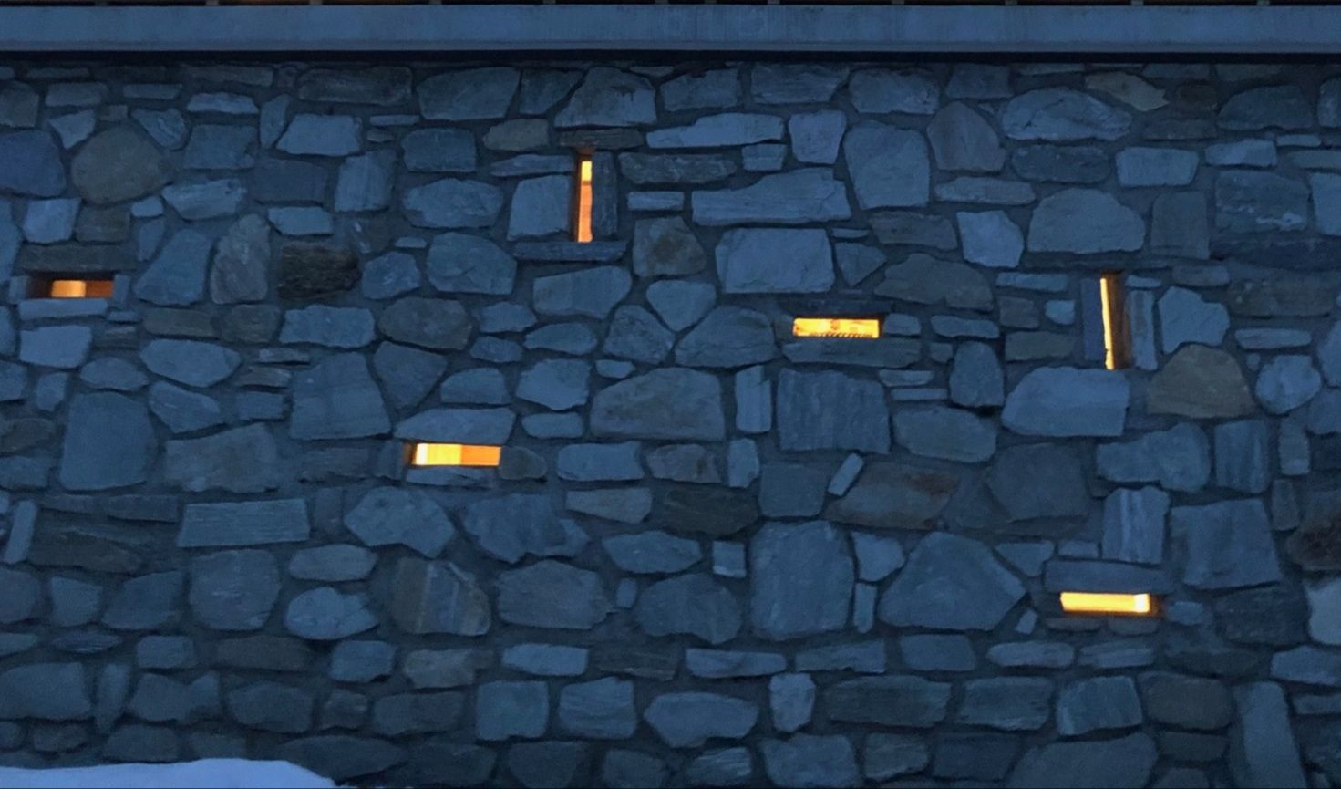 Un mur de pierre avec des lumières dessus la nuit