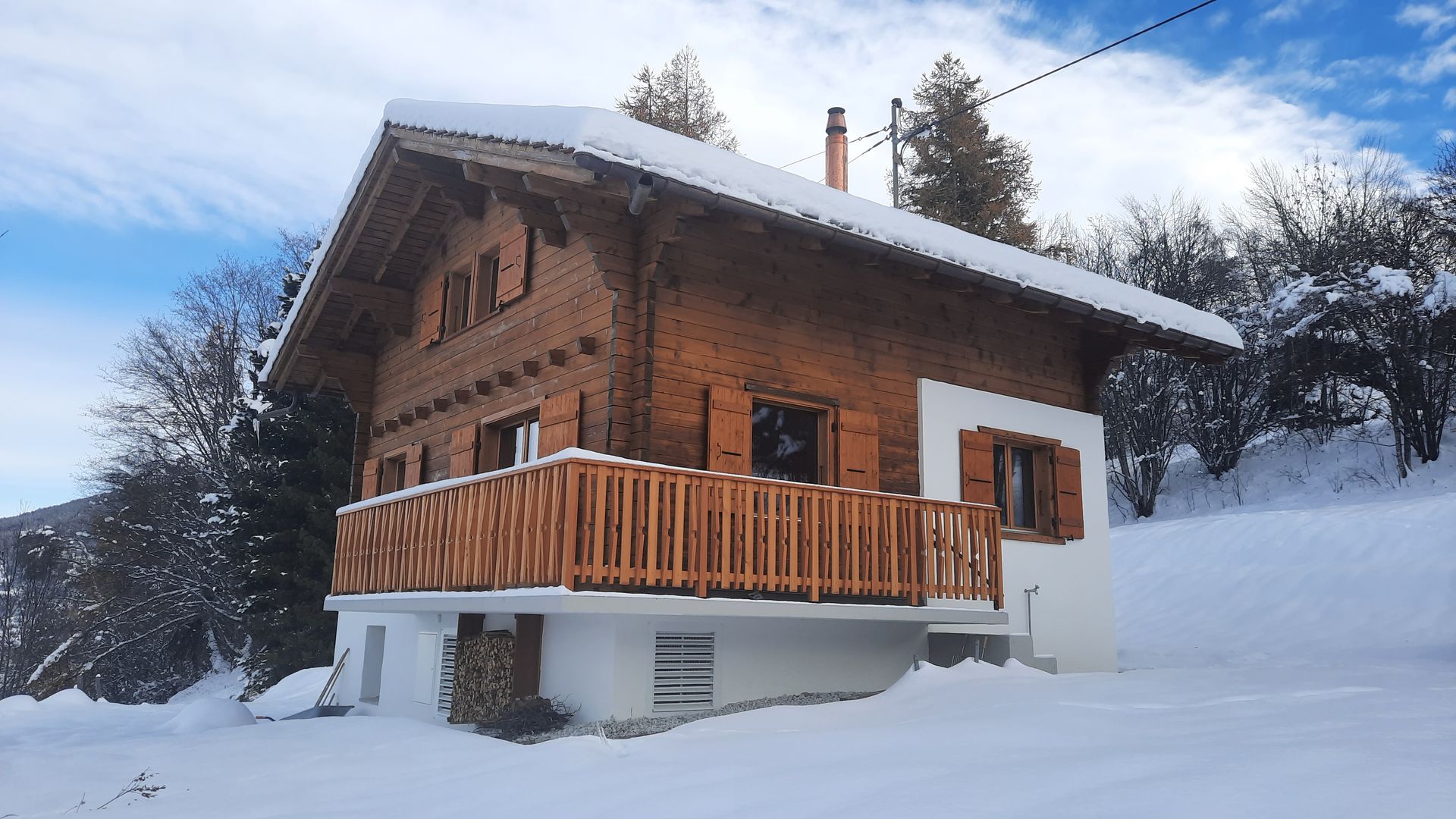 Une petite maison en bois avec un balcon dans la neige