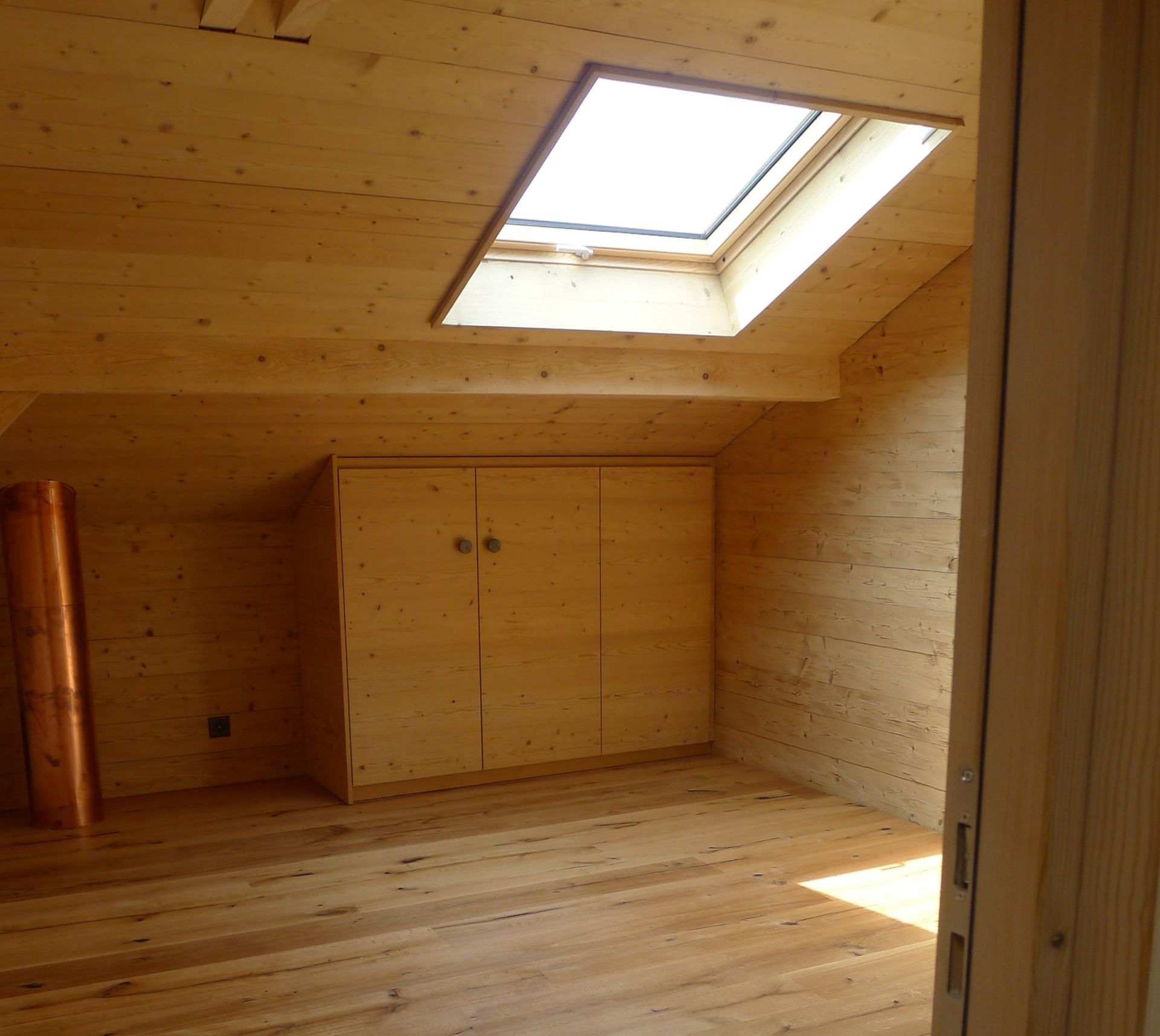 Une pièce avec une lucarne et des armoires en bois