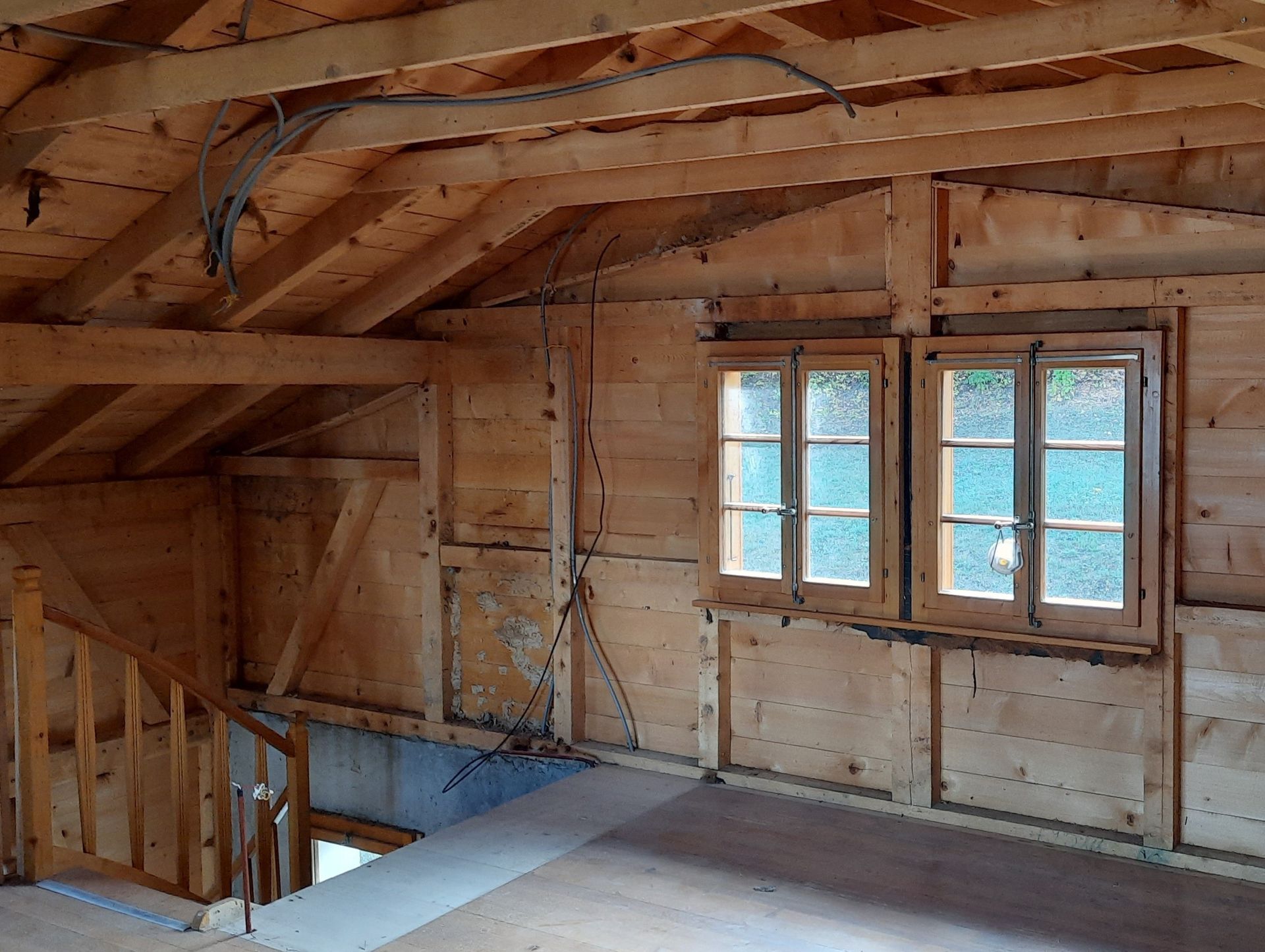 Une pièce en bois avec un escalier et deux fenêtres