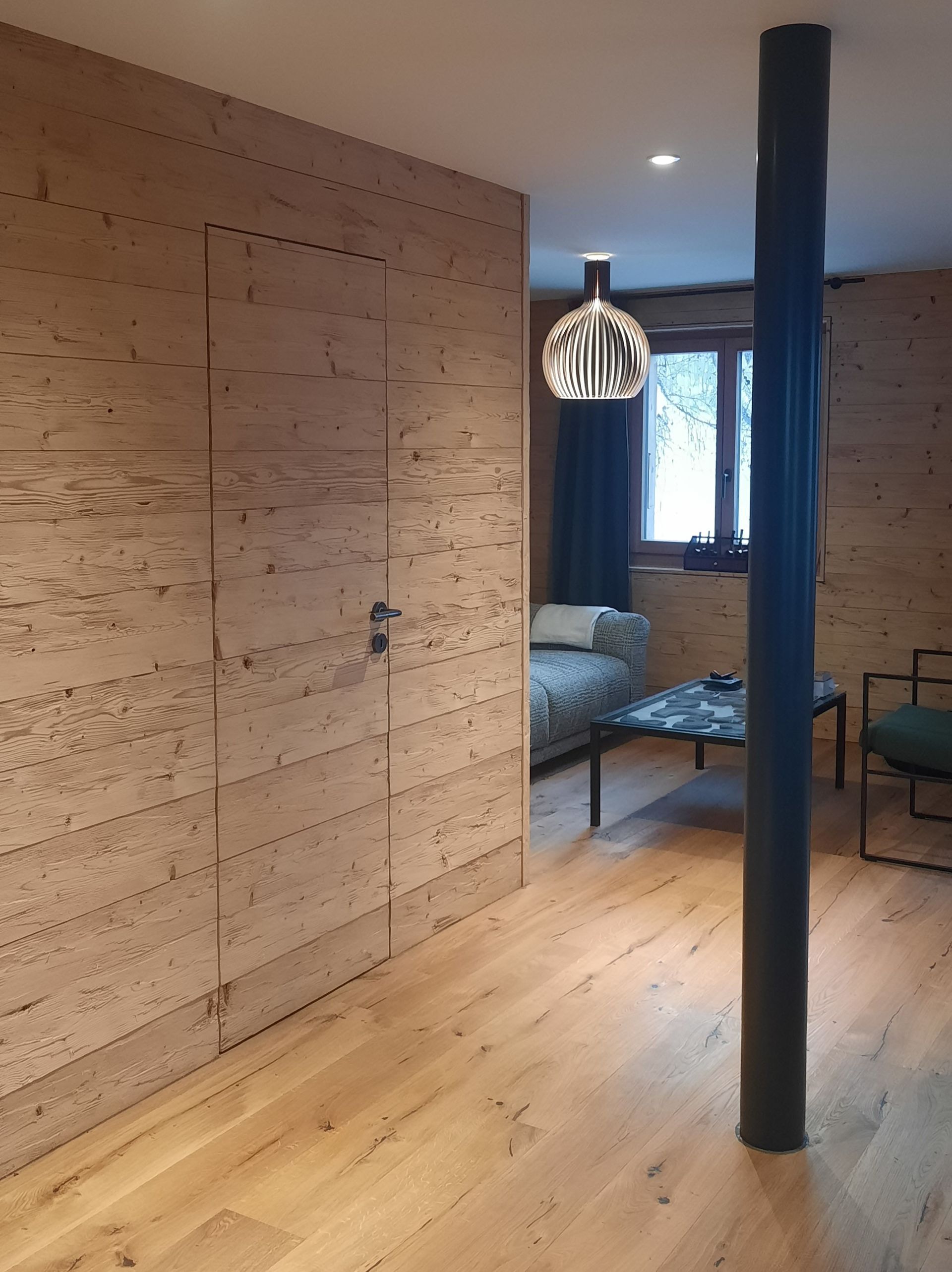 Un salon avec parquet, un canapé et une table.