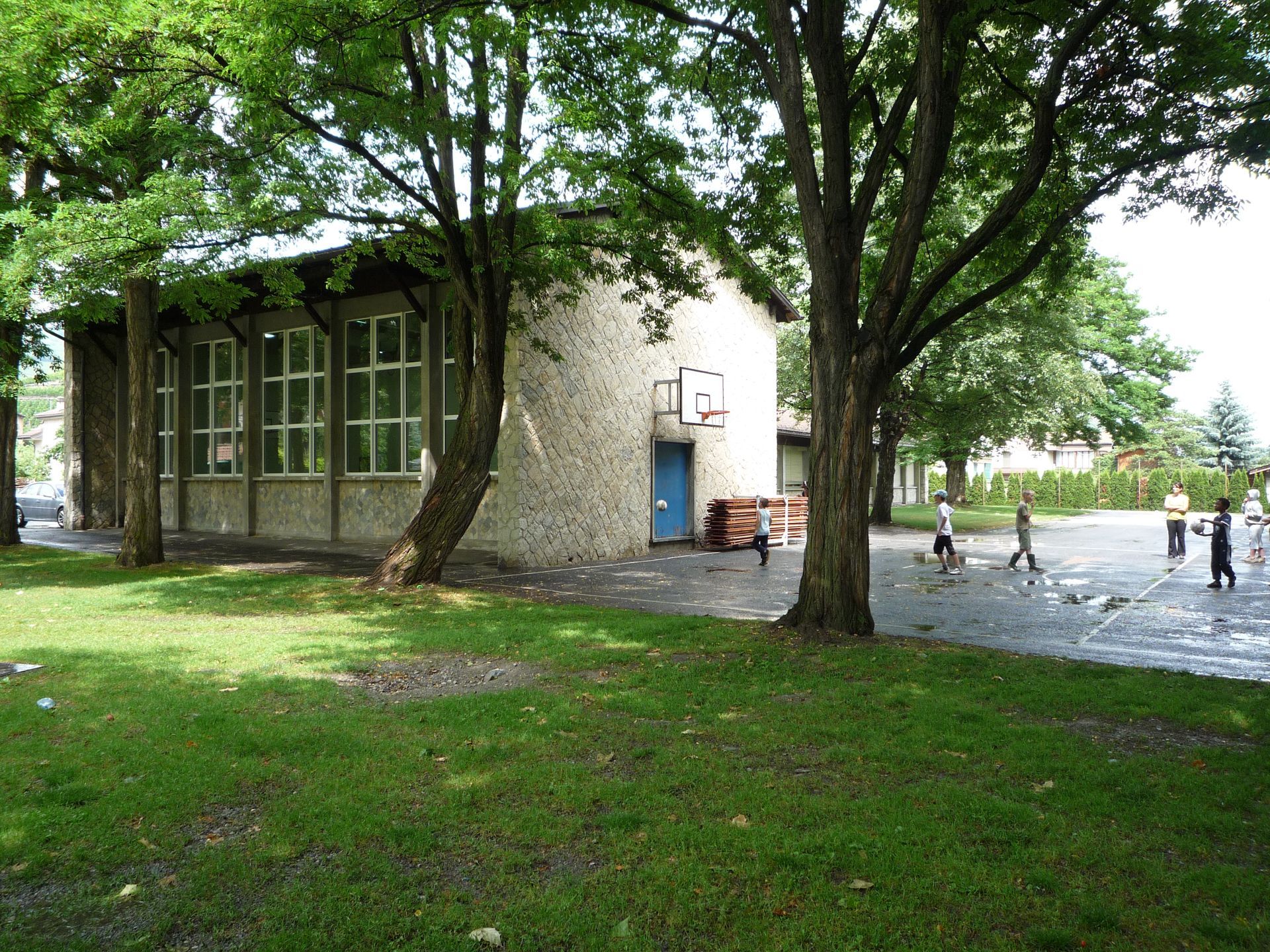 Un bâtiment avec une porte bleue est entouré d'arbres et d'herbe