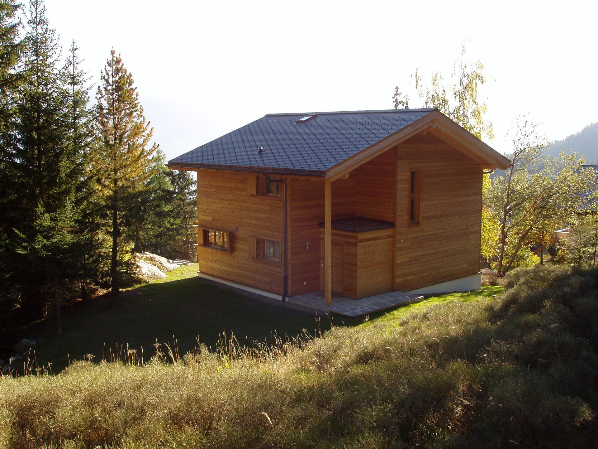 Une petite maison en bois se trouve au sommet d'une colline herbeuse