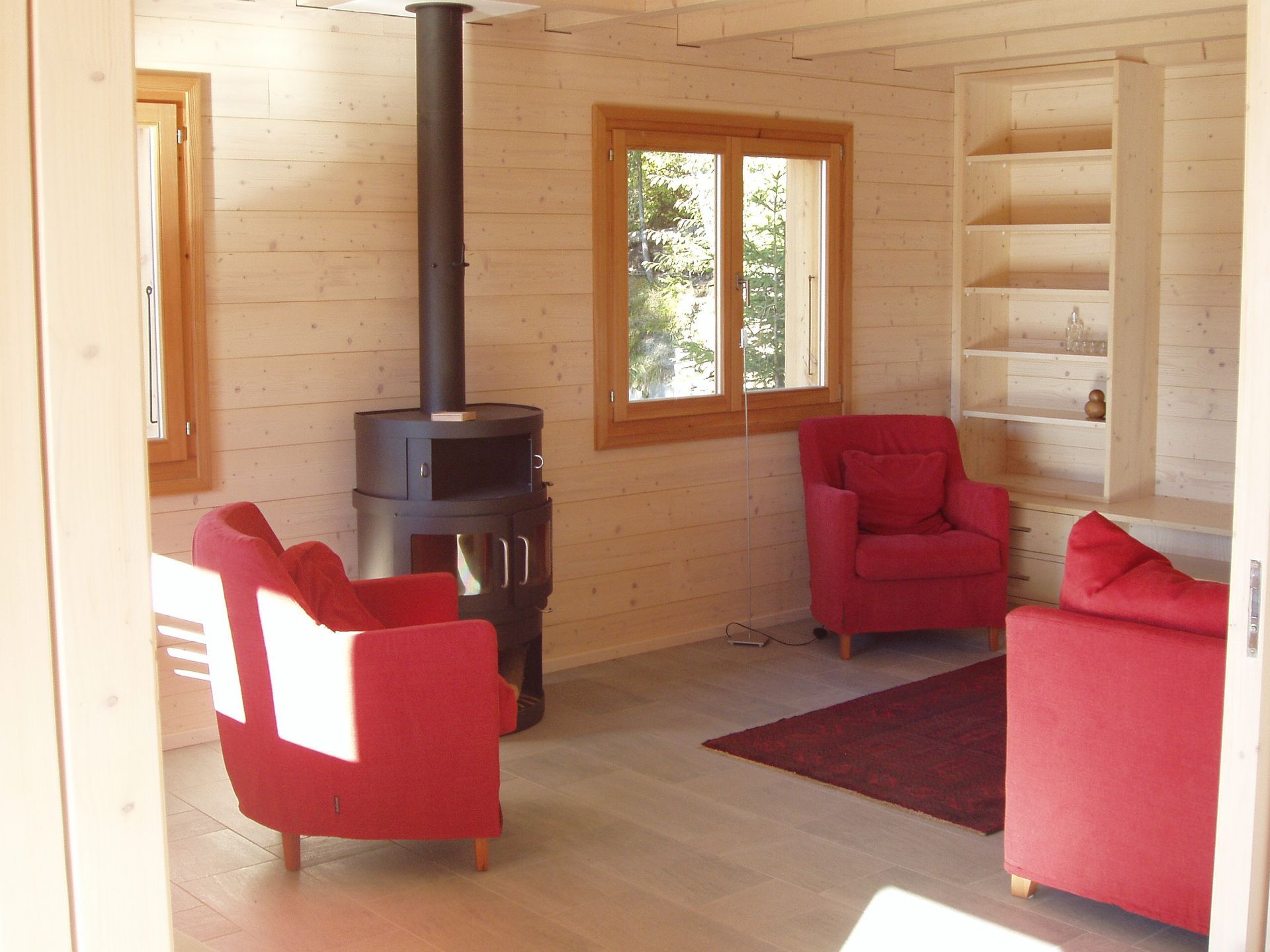 Un salon avec deux chaises rouges et un poêle à bois