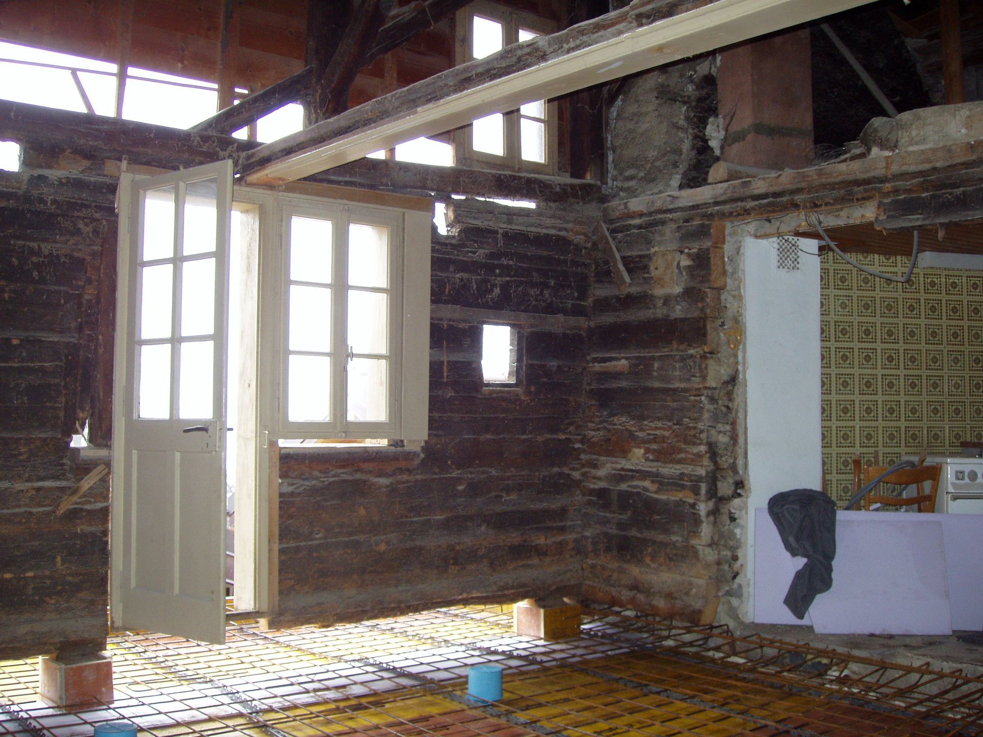 L'intérieur d'une cabane en rondins avec une cuisine et une porte ouverte.