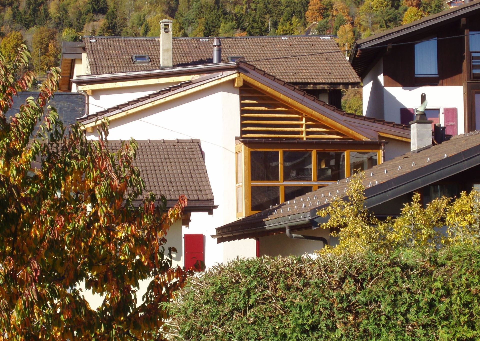 Une maison blanche avec un toit marron est entourée d'arbres