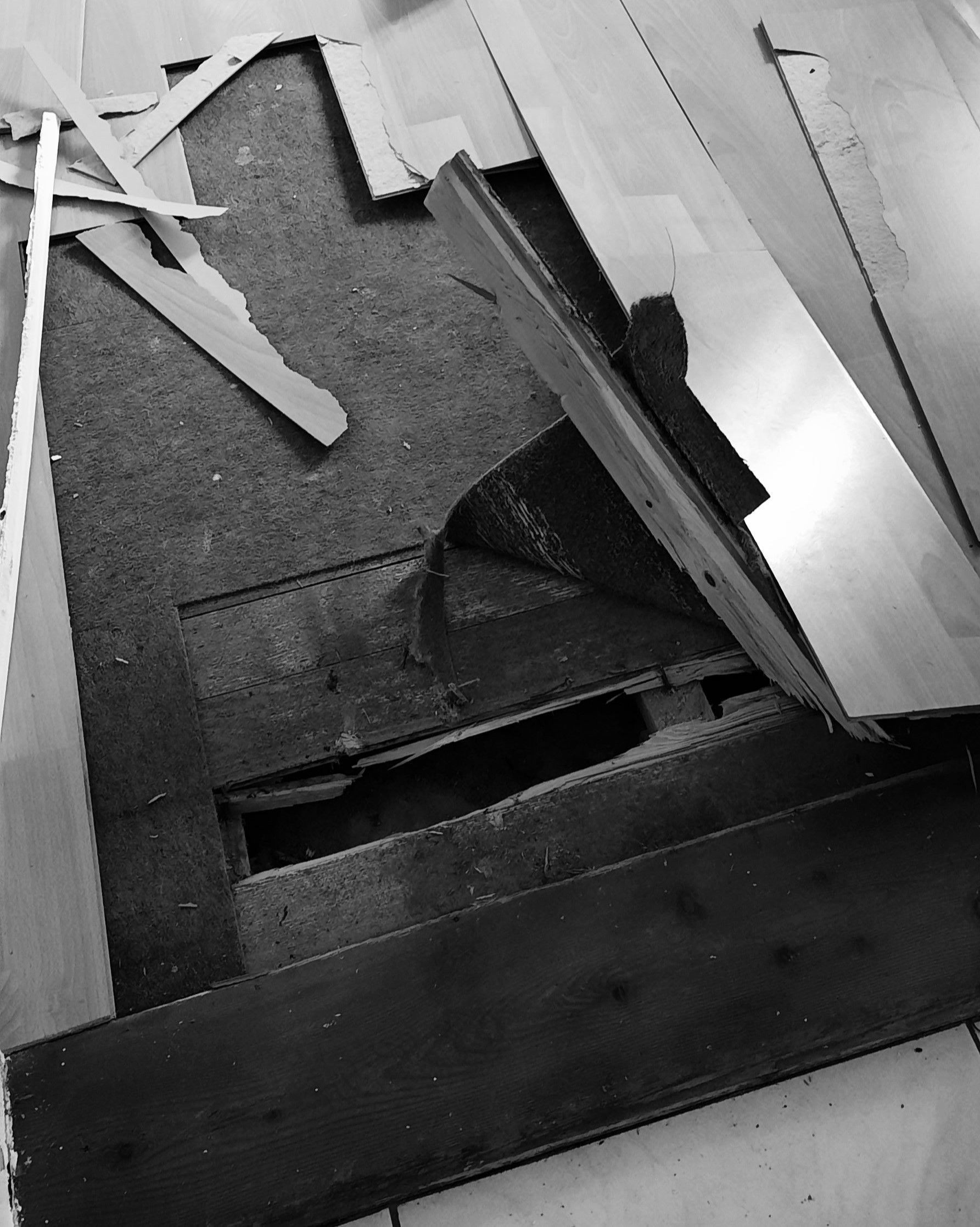 Une photo en noir et blanc d'un plancher en bois avec un trou dedans