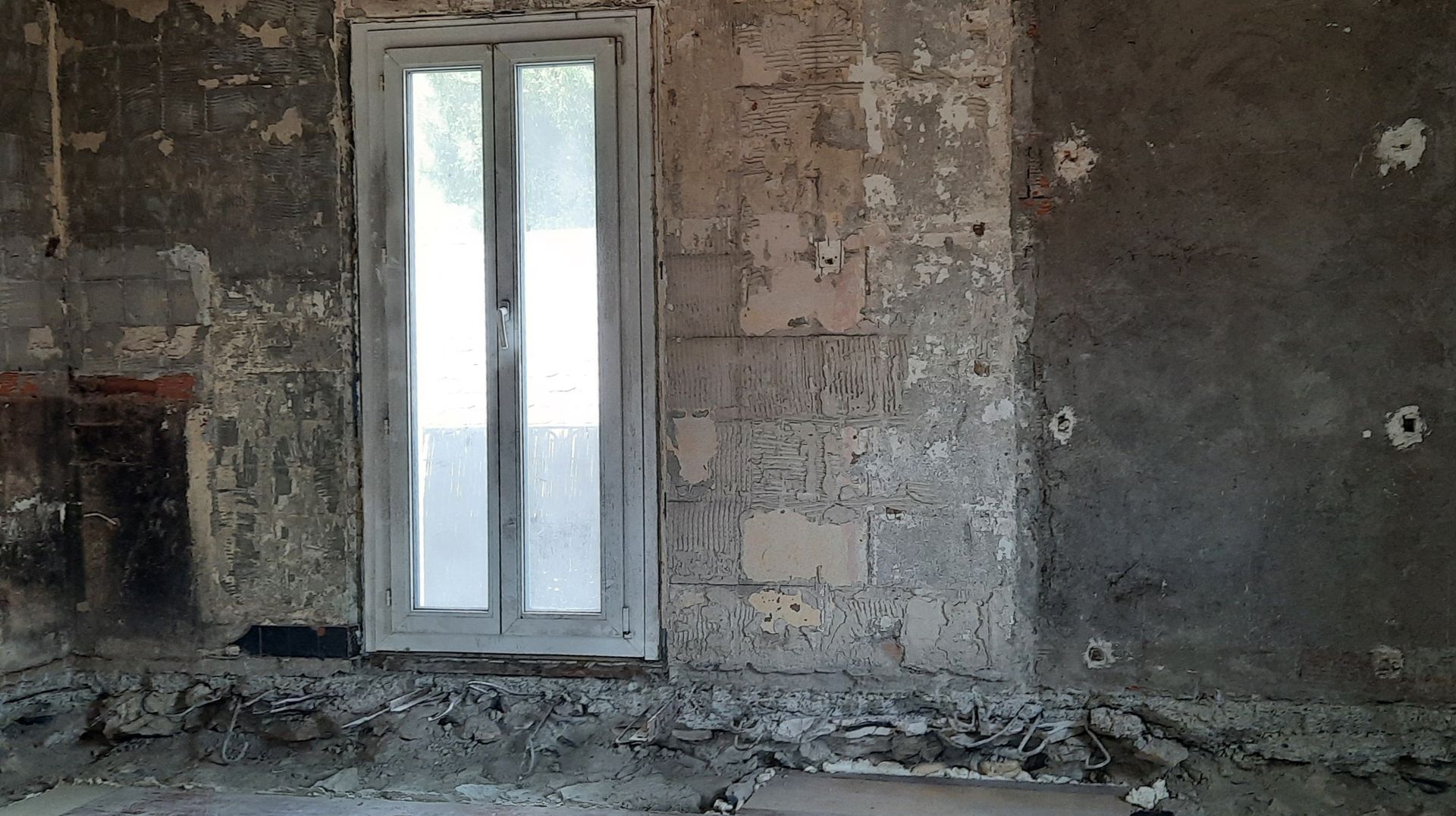 Une pièce vide avec une fenêtre et un mur de briques.