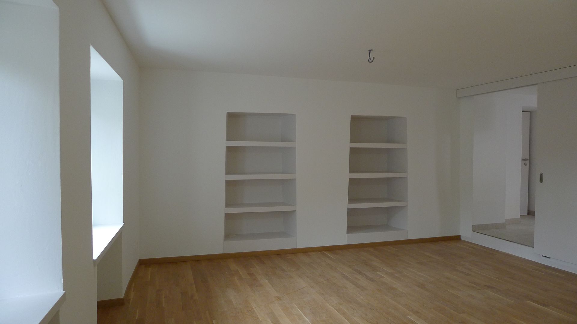 Une pièce vide avec des murs blancs et du parquet