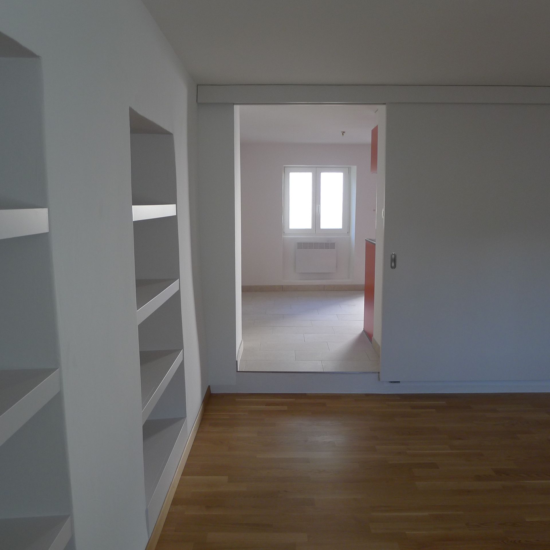 Une pièce vide avec un plancher en bois et des murs blancs