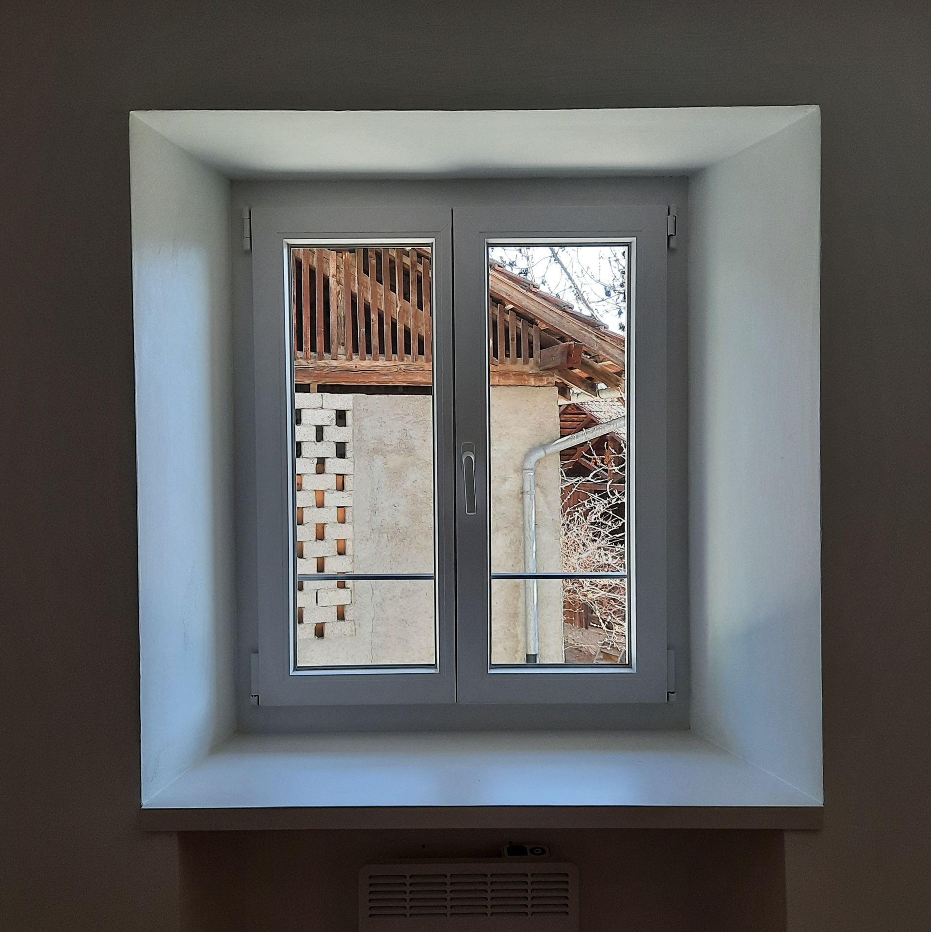 Une fenêtre blanche avec le reflet d'un bâtiment à l'intérieur