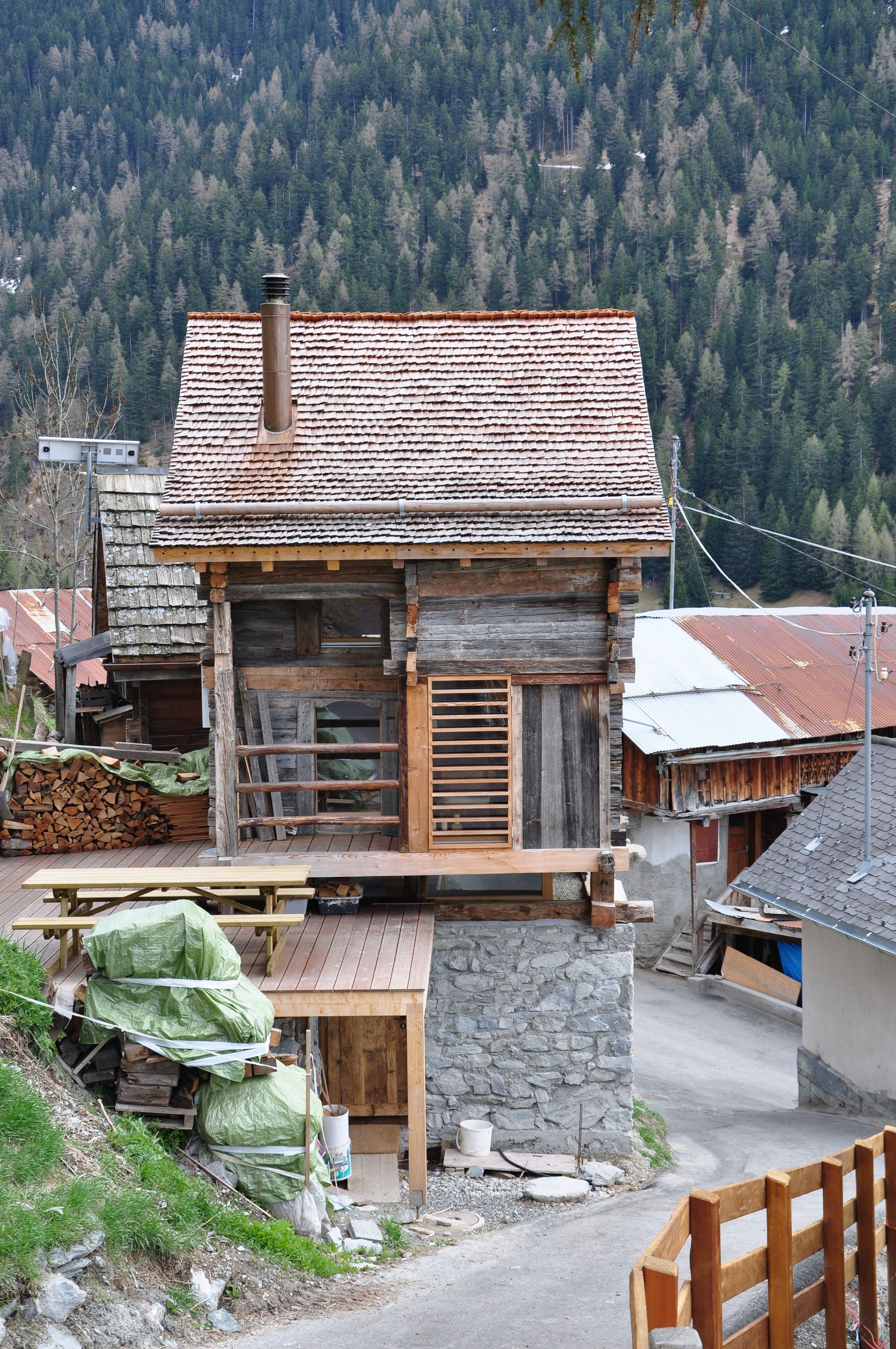 Une petite maison en bois au milieu d'un village avec des arbres en arrière-plan.