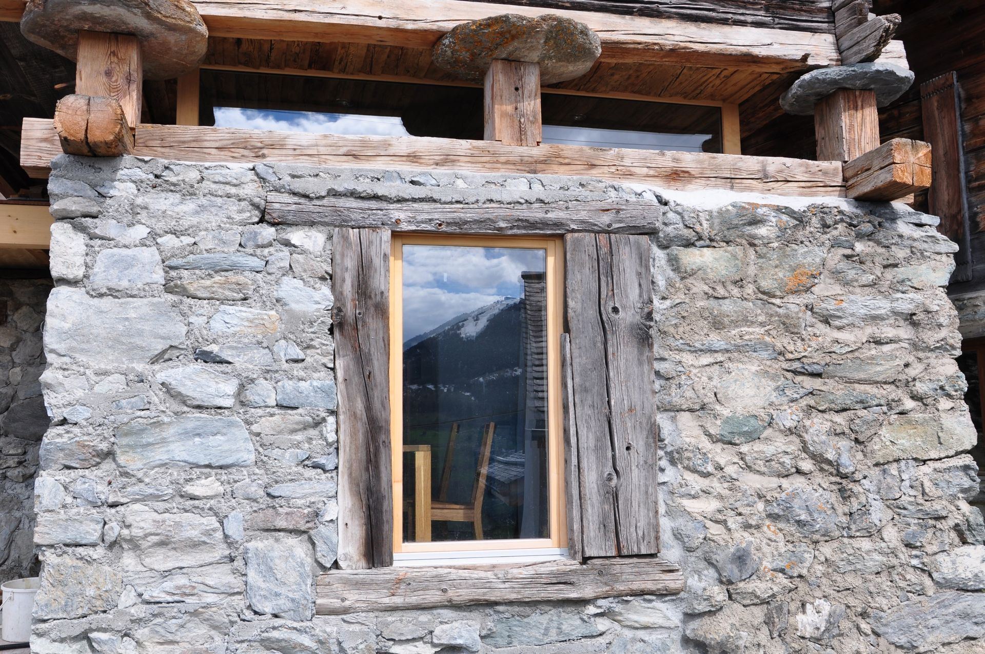 Une fenêtre dans un mur de pierre avec un cadre en bois