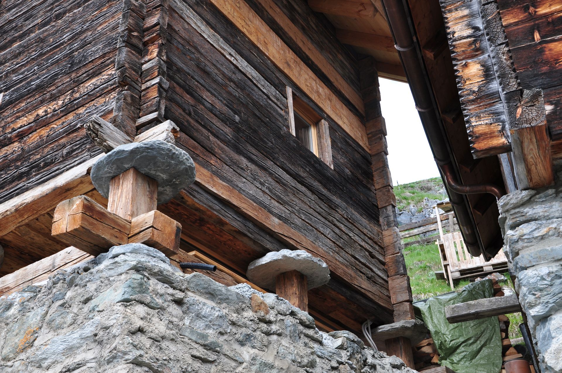 Un bâtiment en bois avec un mur en pierre devant.
