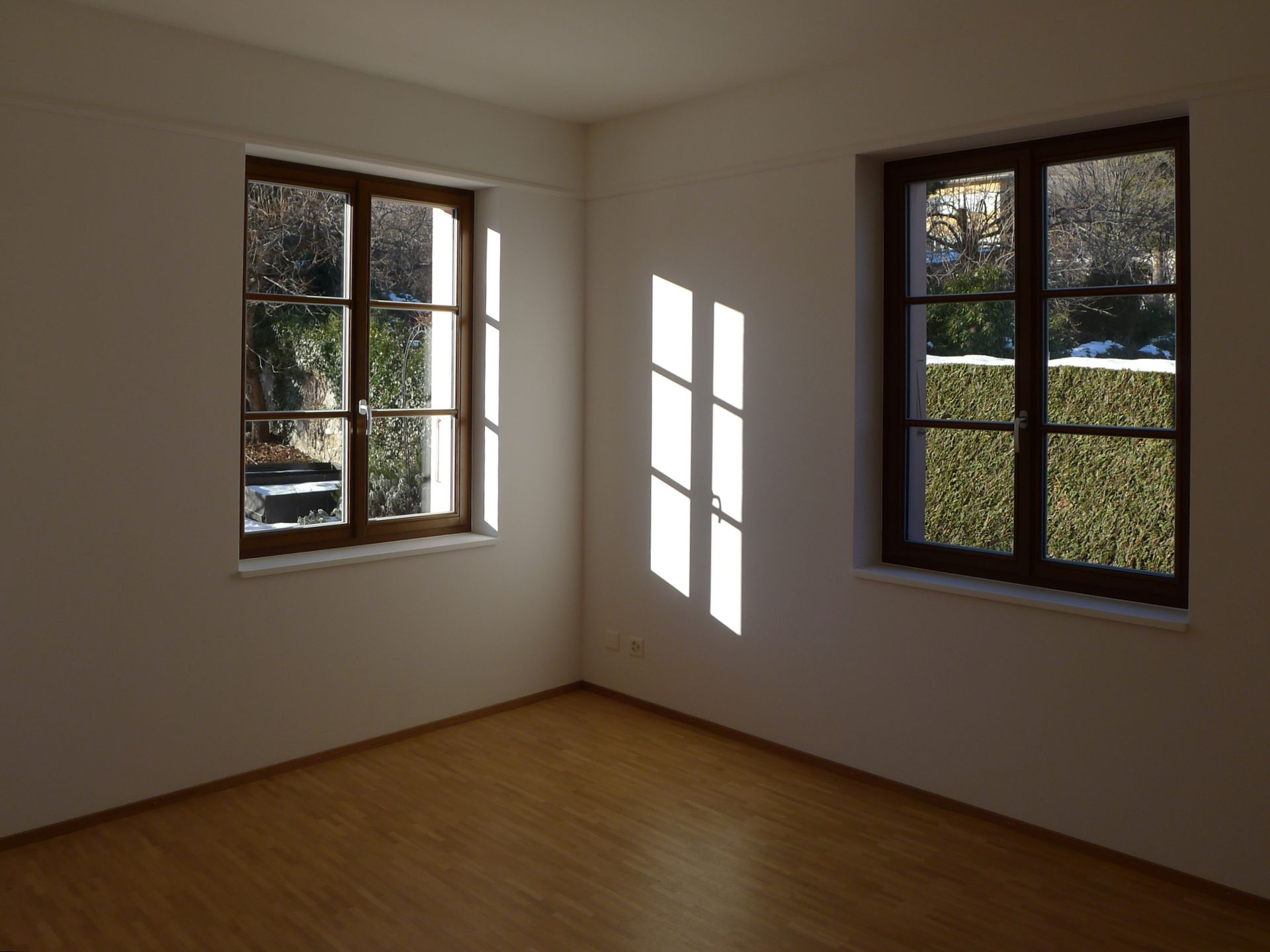 Une pièce vide avec deux fenêtres et un plancher en bois