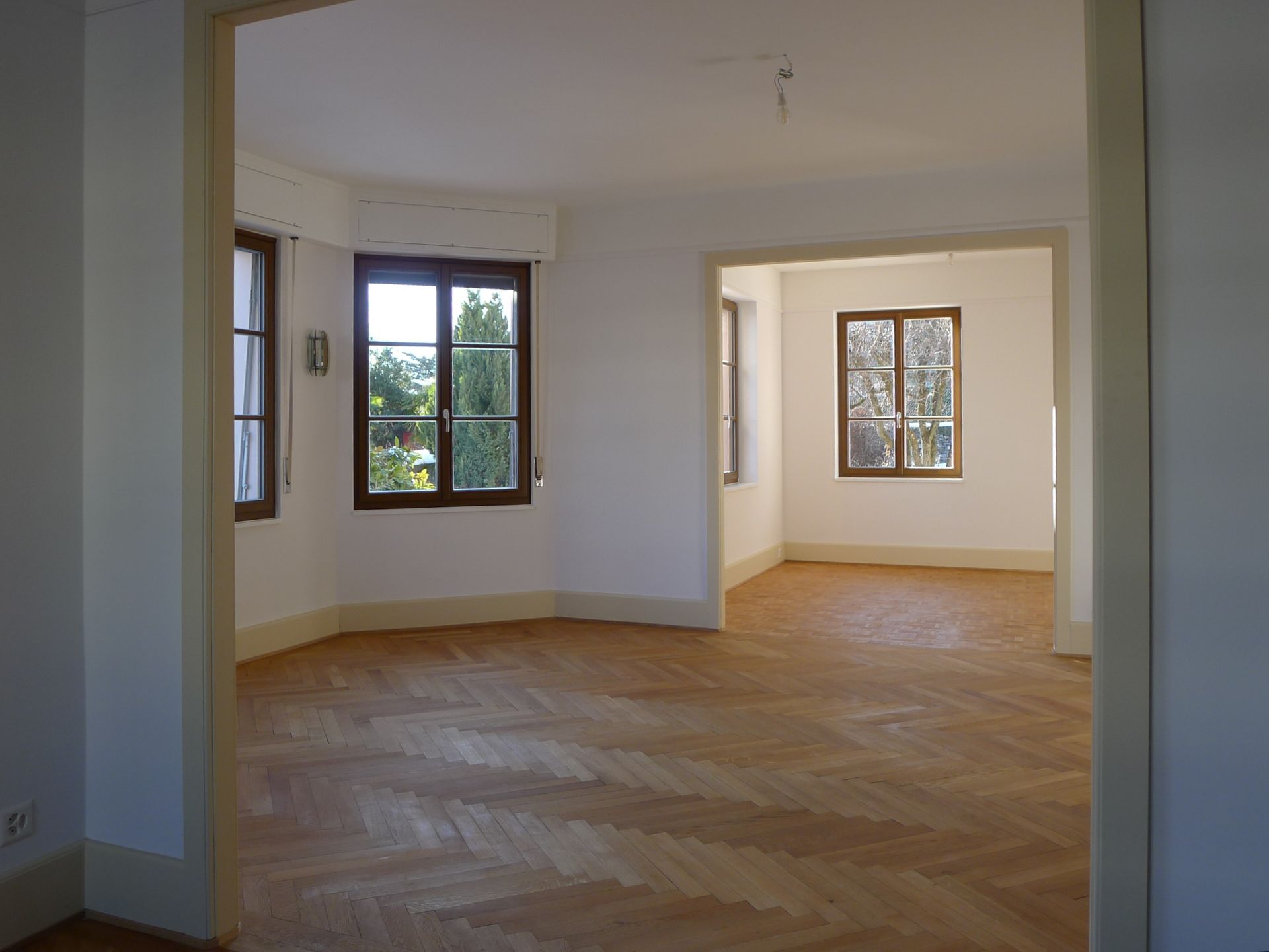 Une pièce vide avec un plancher en bois et deux fenêtres