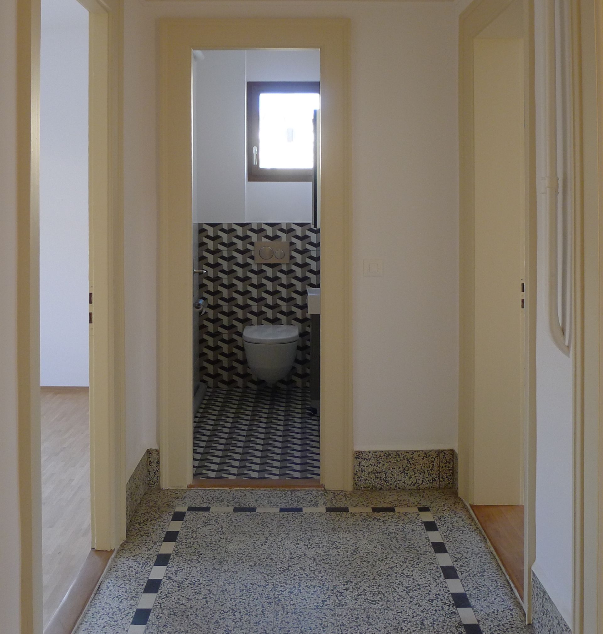 Un couloir menant à une salle de bain avec WC