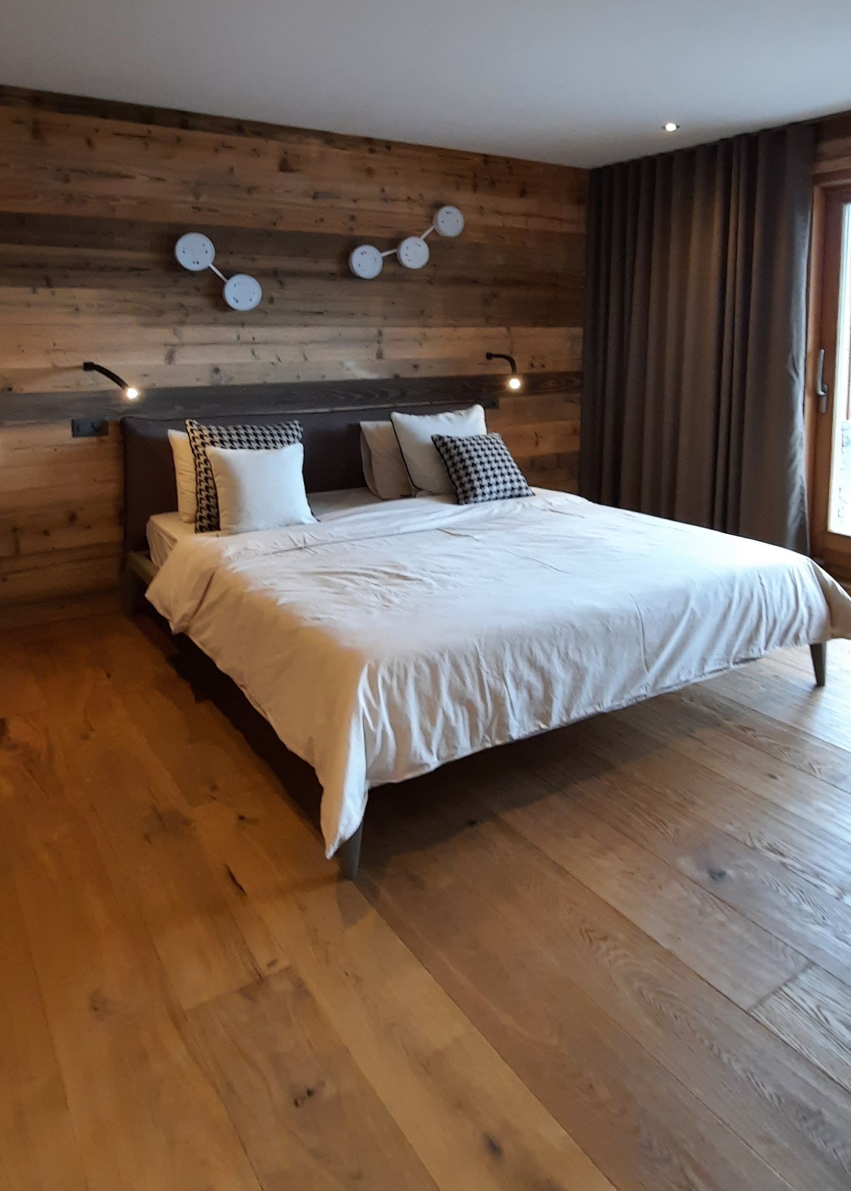Une chambre avec un grand lit et du parquet.
