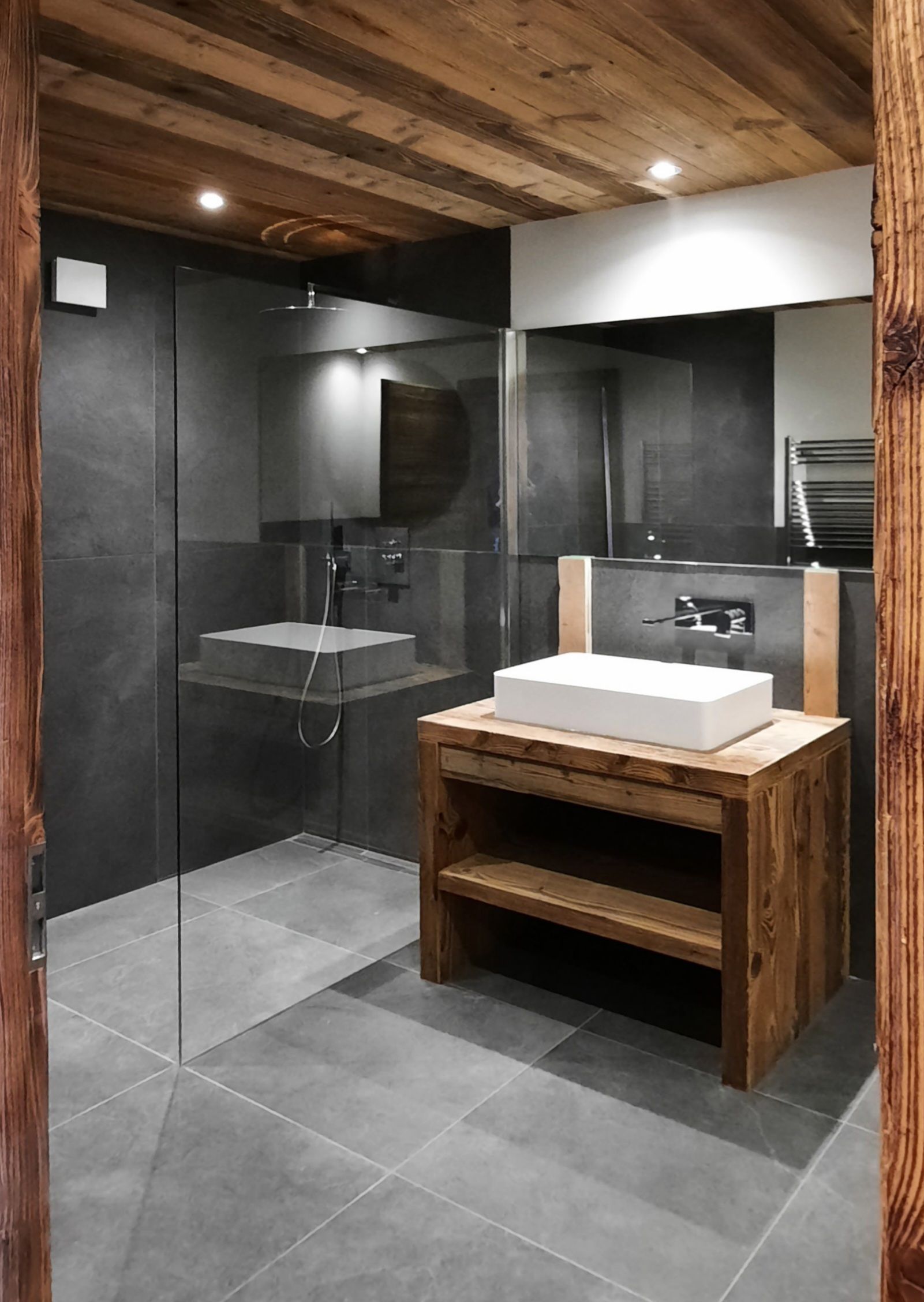 Une salle de bain avec lavabo, miroir et douche à l'italienne.