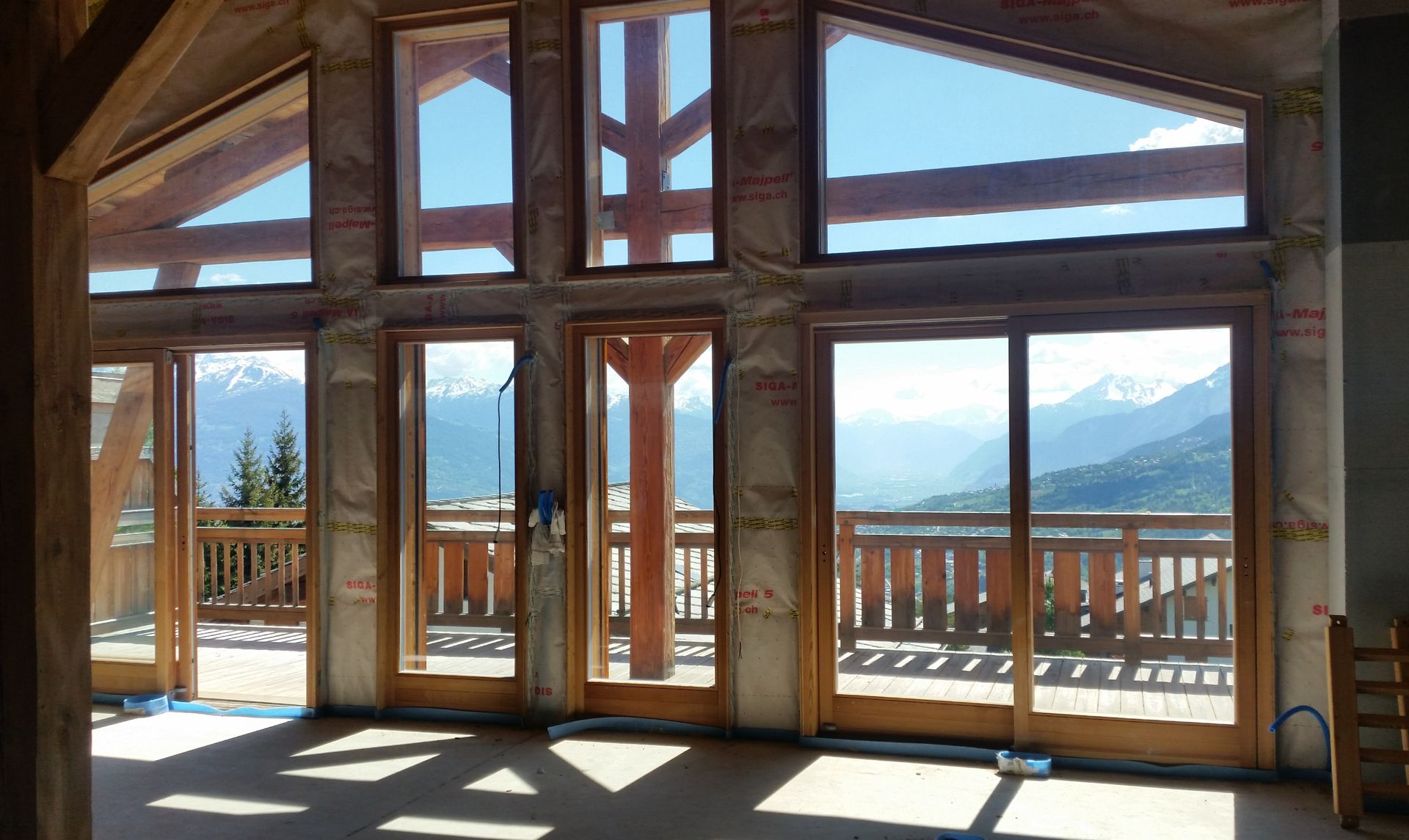 Une pièce avec beaucoup de fenêtres et un balcon avec des montagnes en arrière-plan