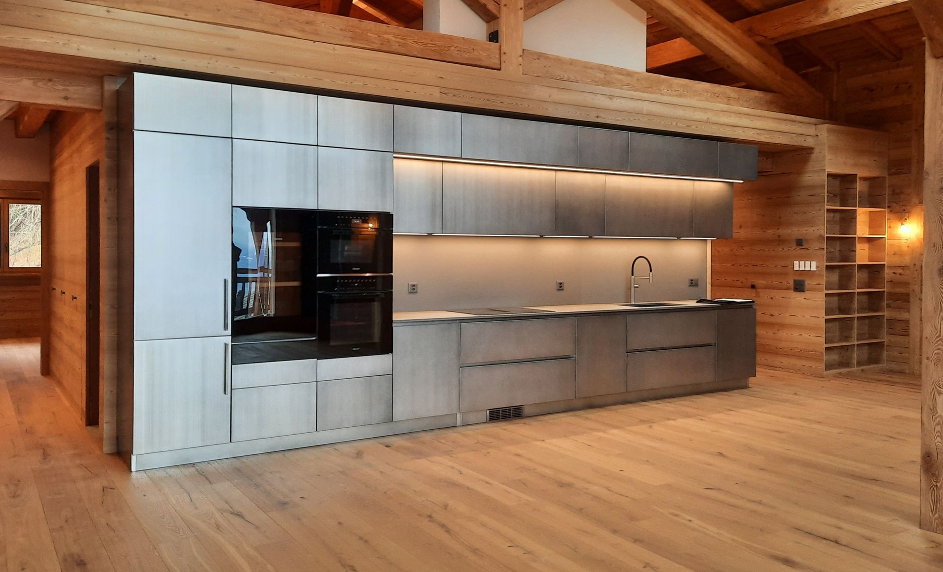 Une cuisine avec des armoires en acier inoxydable et des planchers en bois