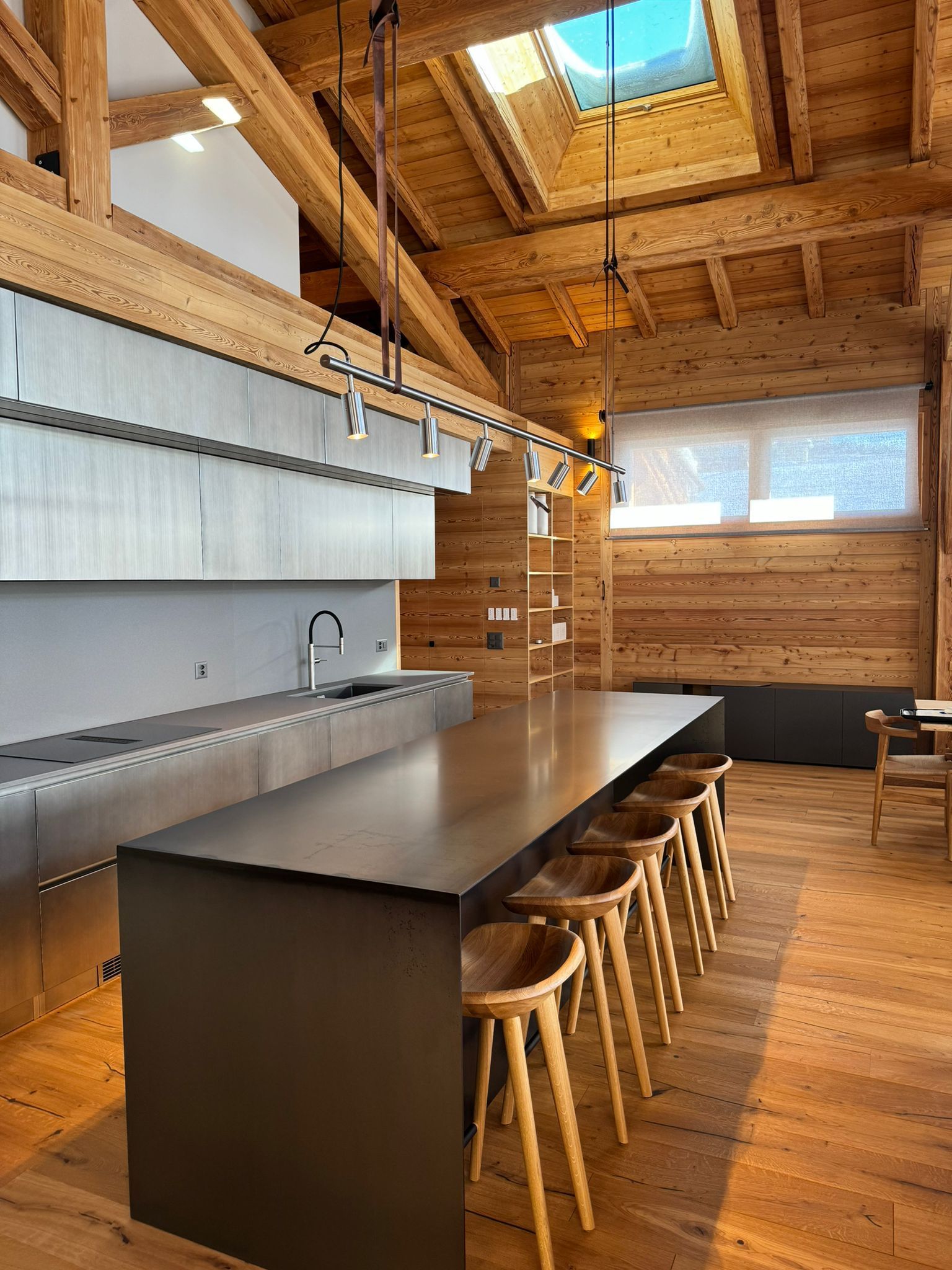 Une cuisine avec une longue table et des tabourets dans une maison en bois.