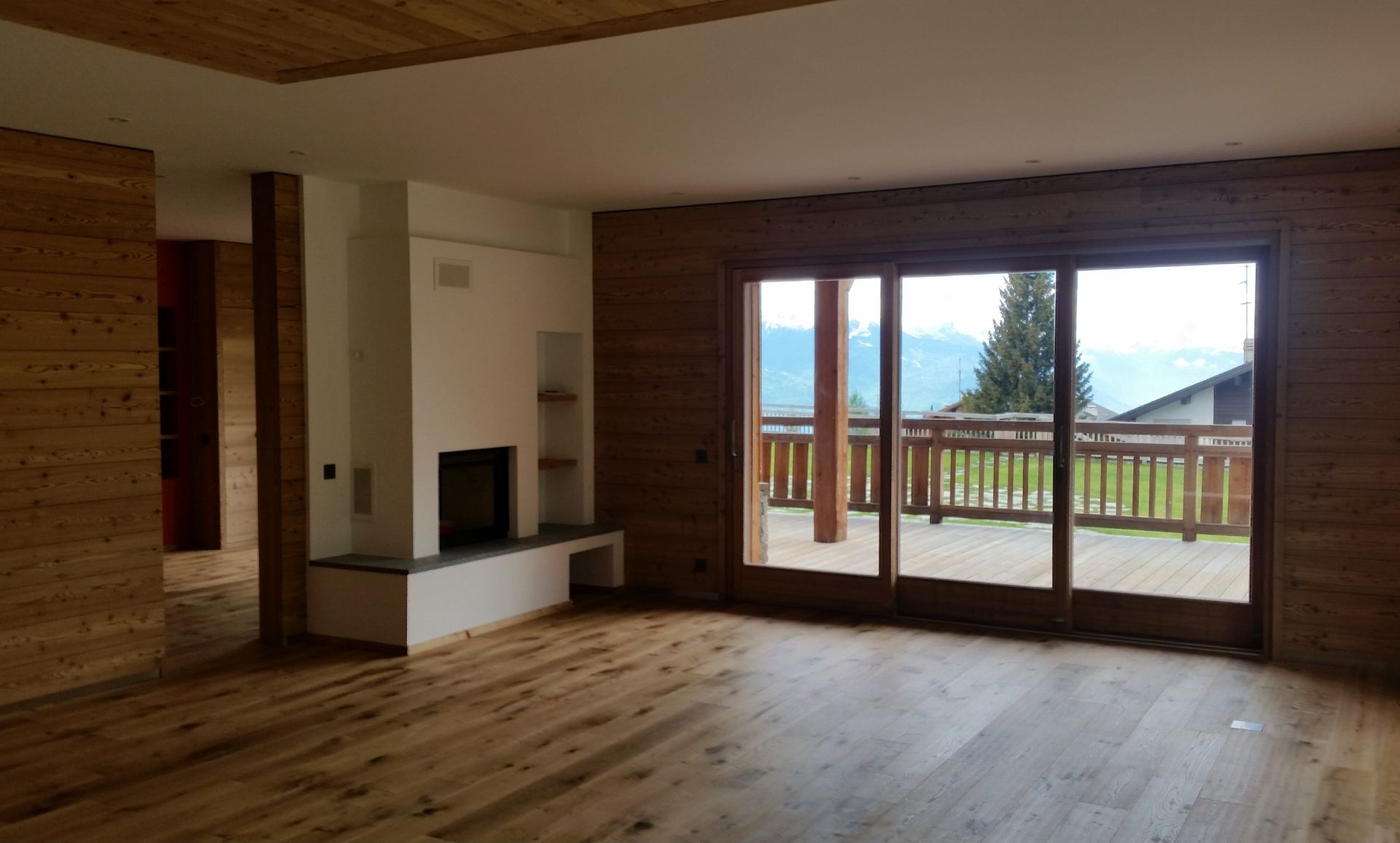 Un salon vide avec du parquet et une cheminée.