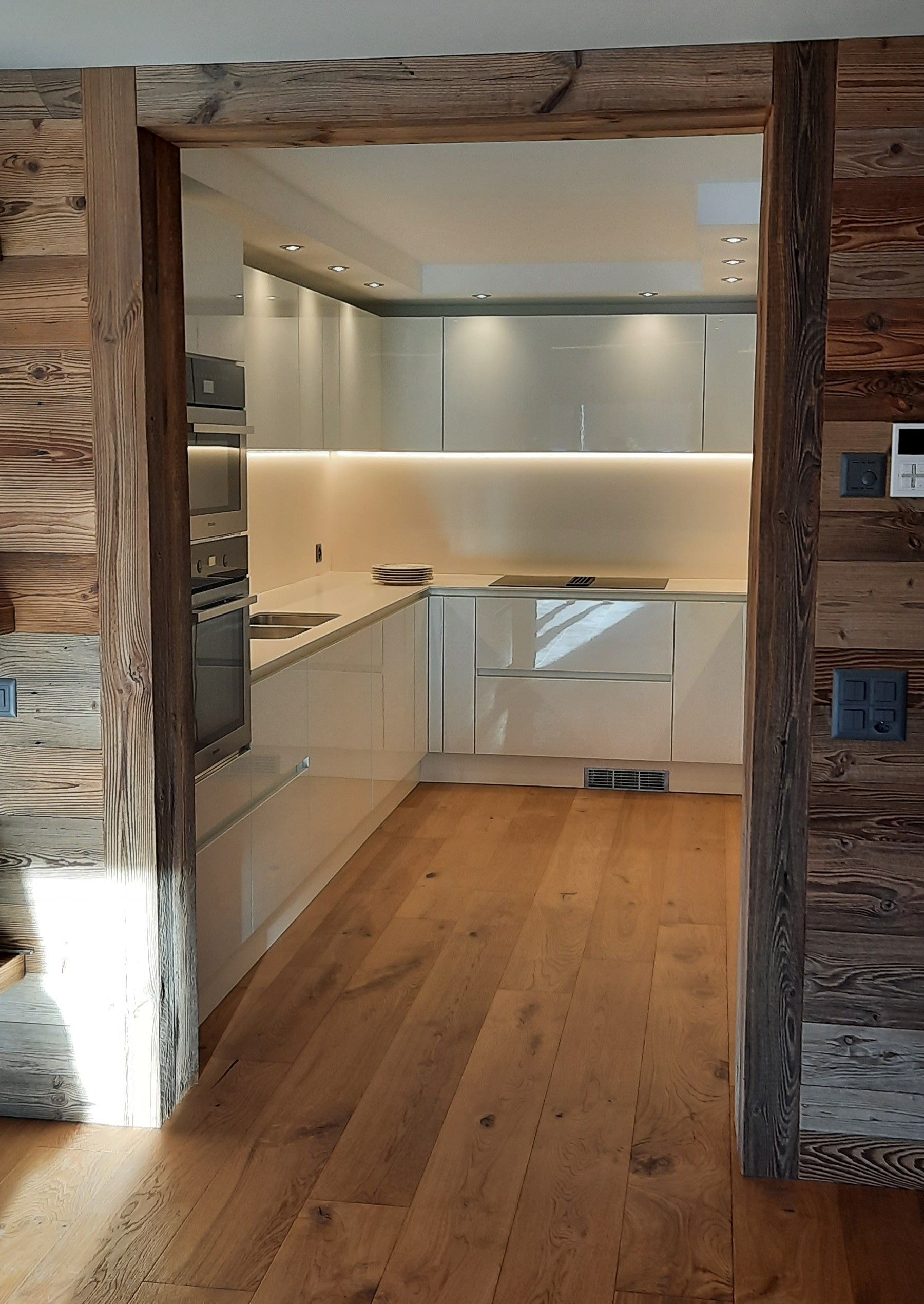 Une cuisine avec des armoires blanches et du parquet