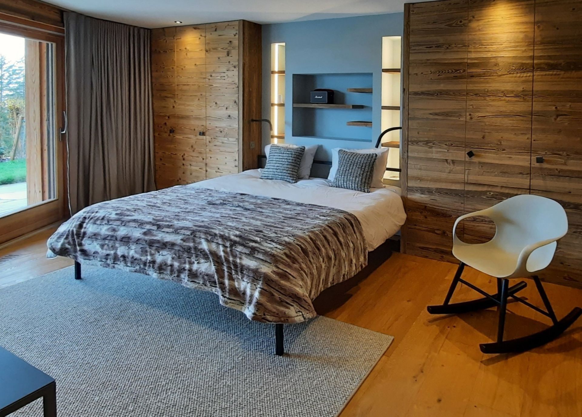 Une chambre avec un grand lit et une chaise à bascule.