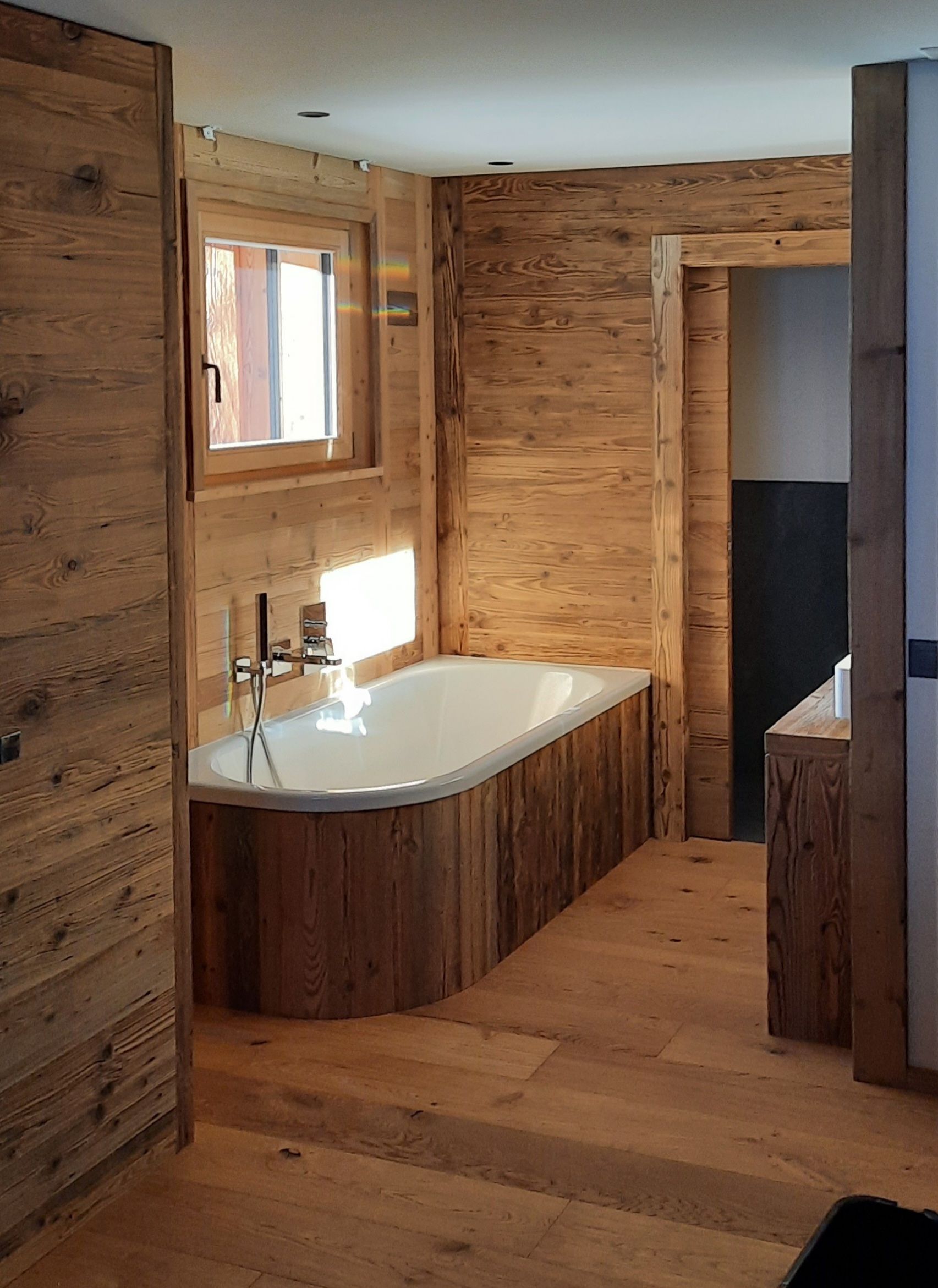 Une baignoire dans une salle de bain avec murs et sols en bois.