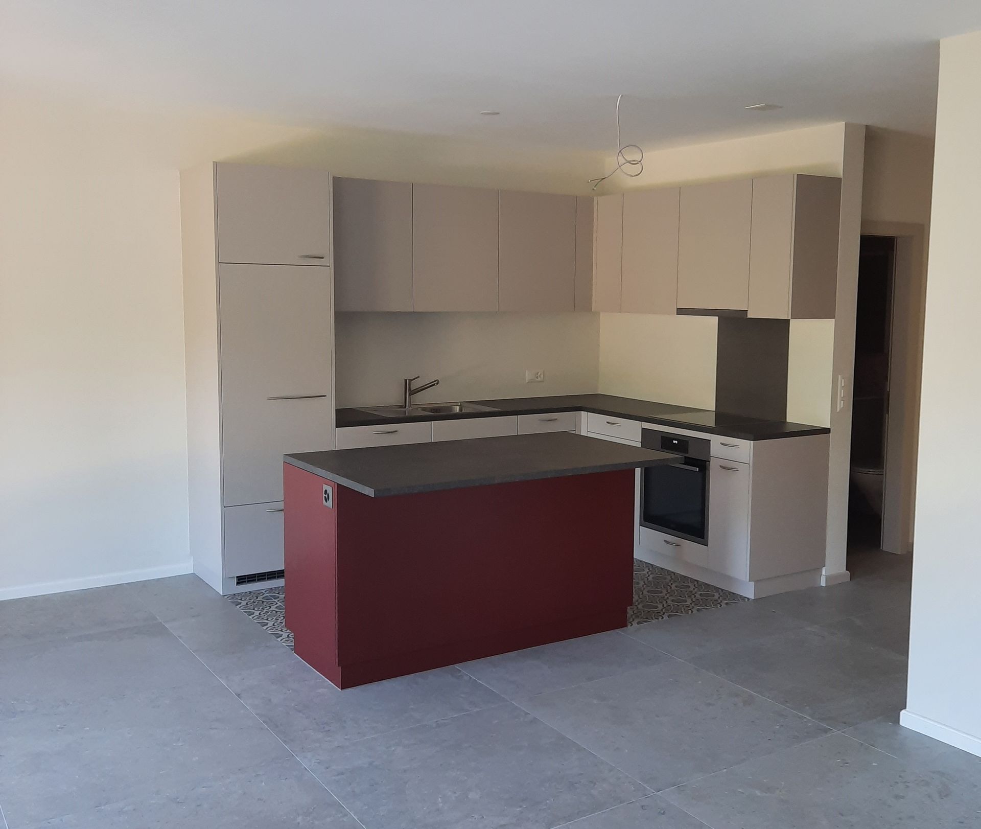 Une cuisine vide avec un îlot rouge au milieu
