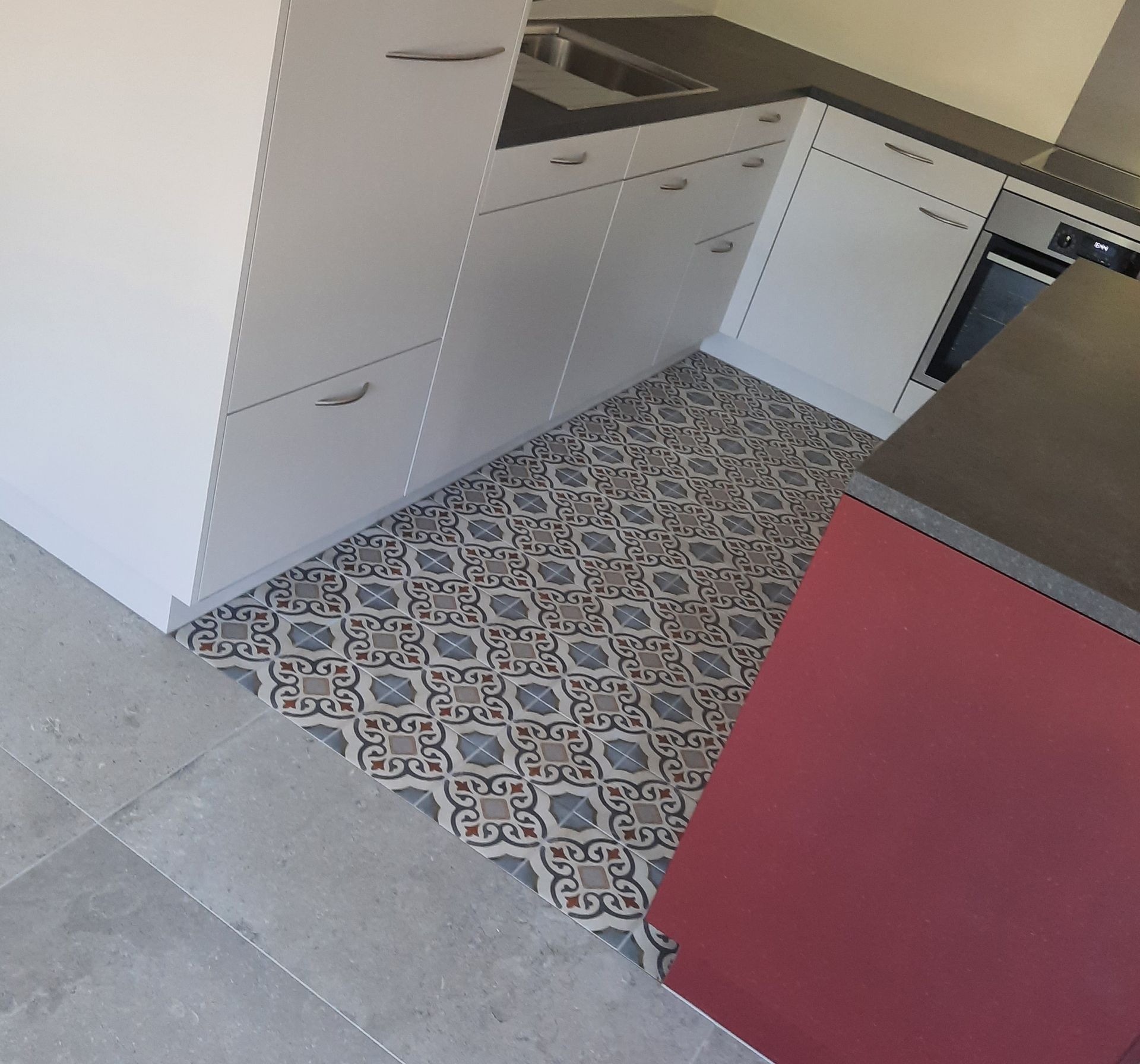 Une cuisine avec des armoires blanches et un îlot rouge