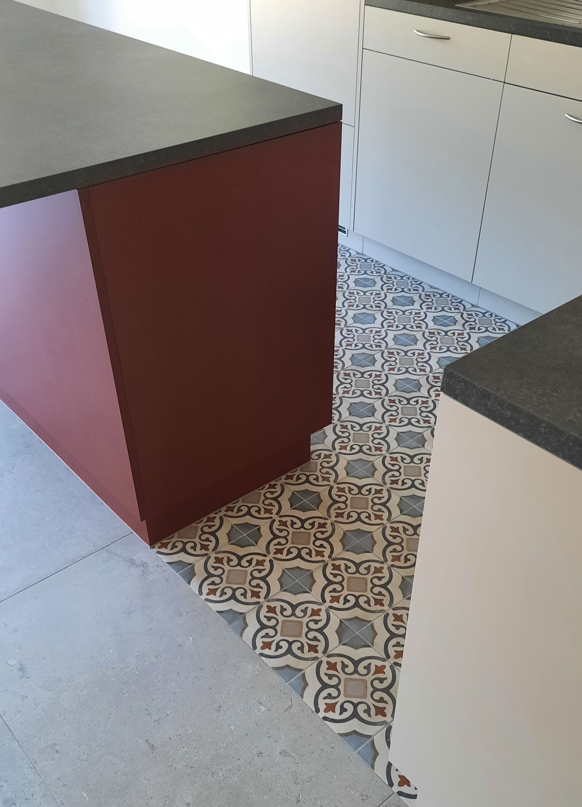 Une cuisine avec un sol carrelé et un îlot rouge