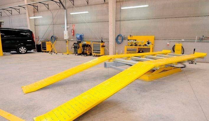 Una rampa amarilla está en un garaje al lado de una camioneta negra.