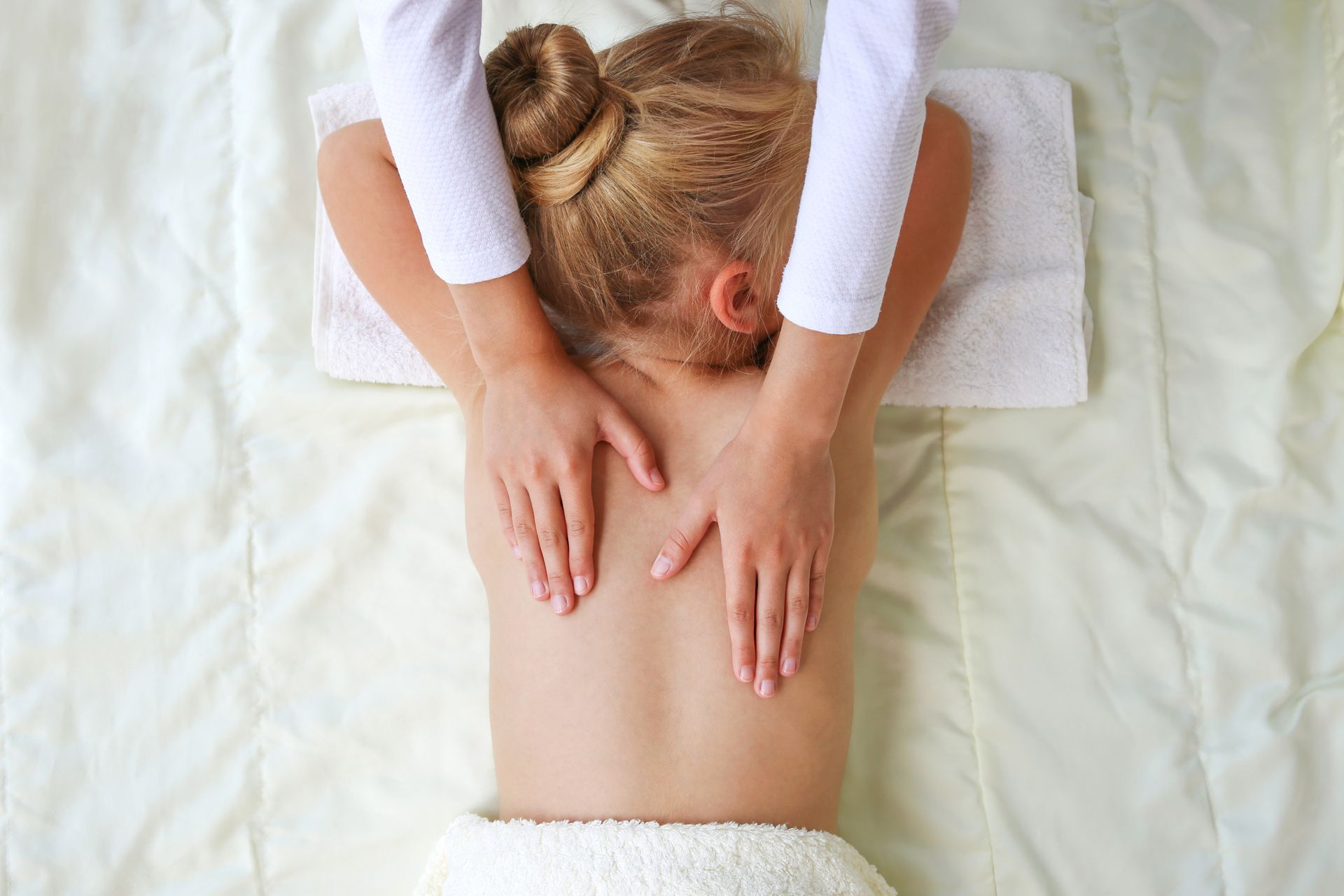 Photo d'une petite fille en train de se faire masser le dos par une femme