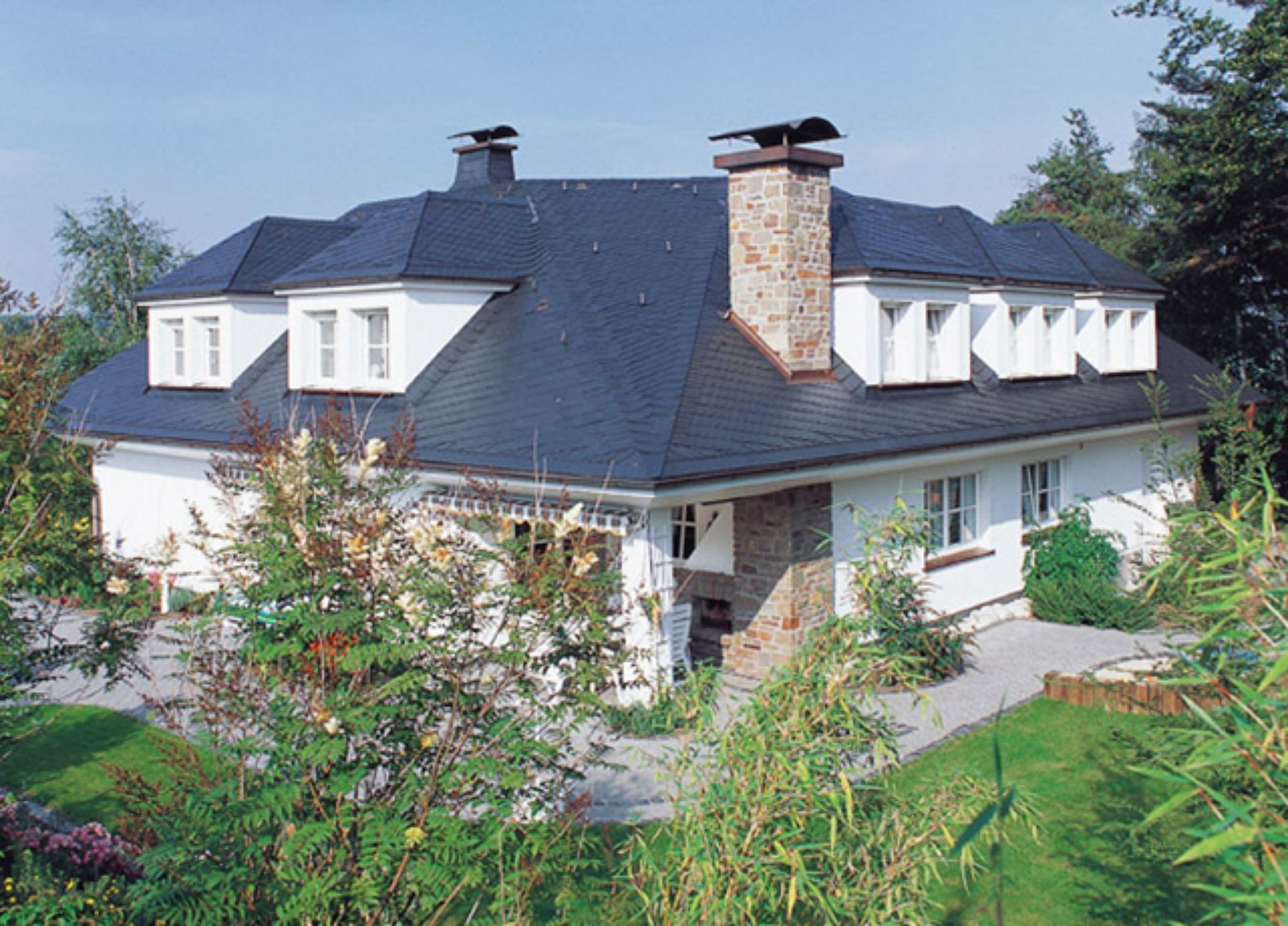 Ein großes weißes Haus mit schwarzem Dach und Schornsteinen.