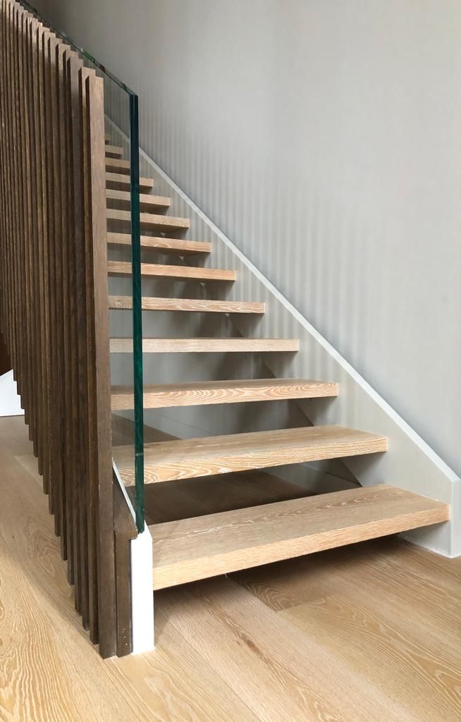 Una escalera de madera con barandilla de cristal en una casa.