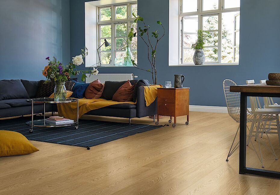 Una sala de estar con sofá, mesa, sillas y paredes azules.