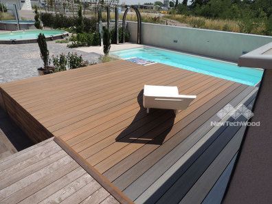 Una silla se encuentra en una terraza de madera junto a una piscina.