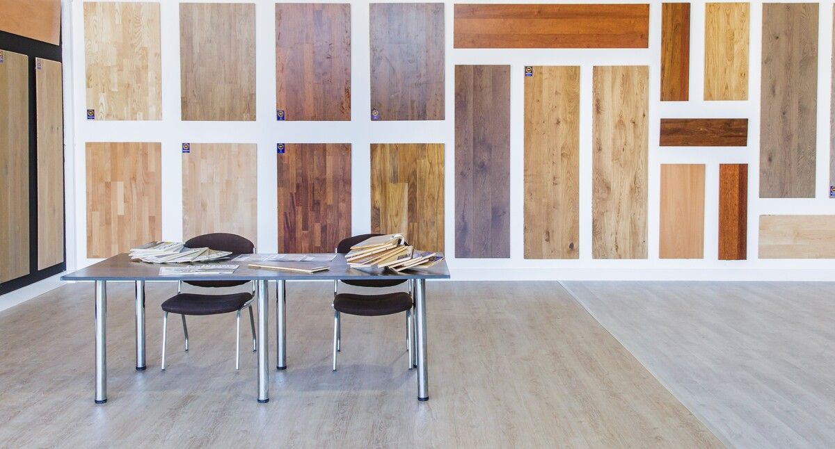 Una habitación con una mesa y sillas frente a una pared de muestras de madera.