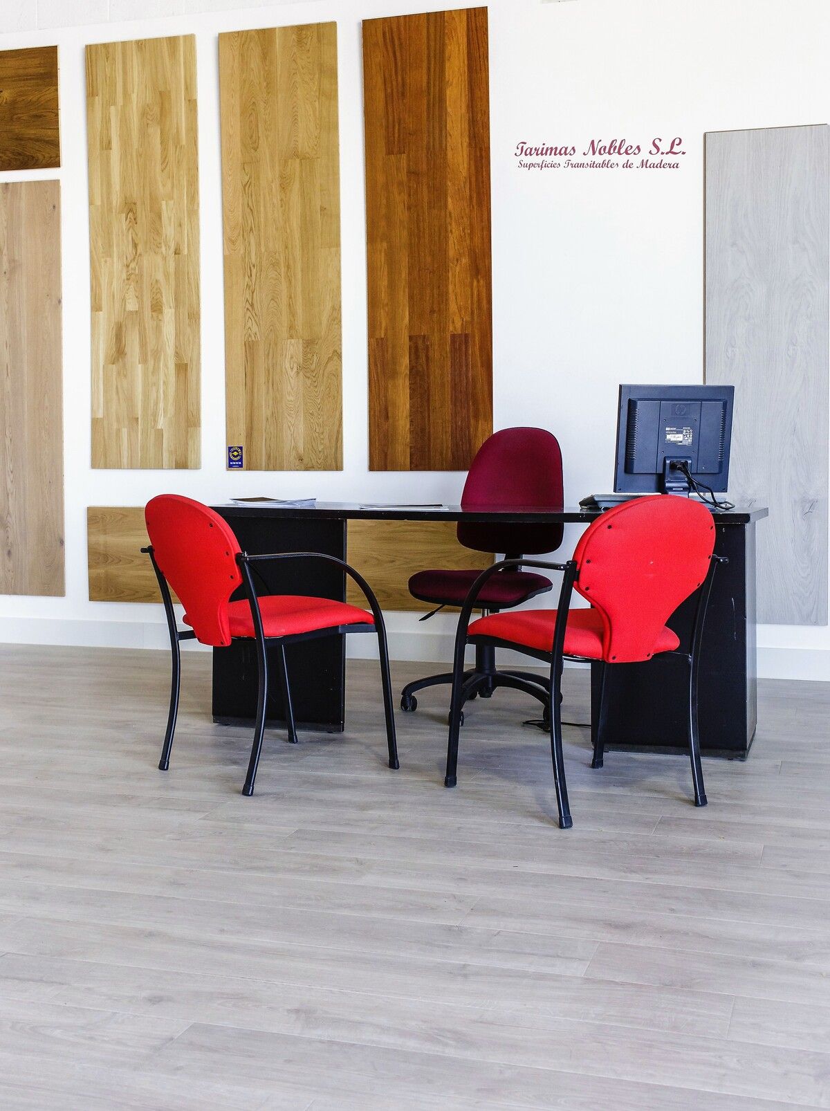 Hay dos sillas rojas frente a un escritorio con una computadora encima.
