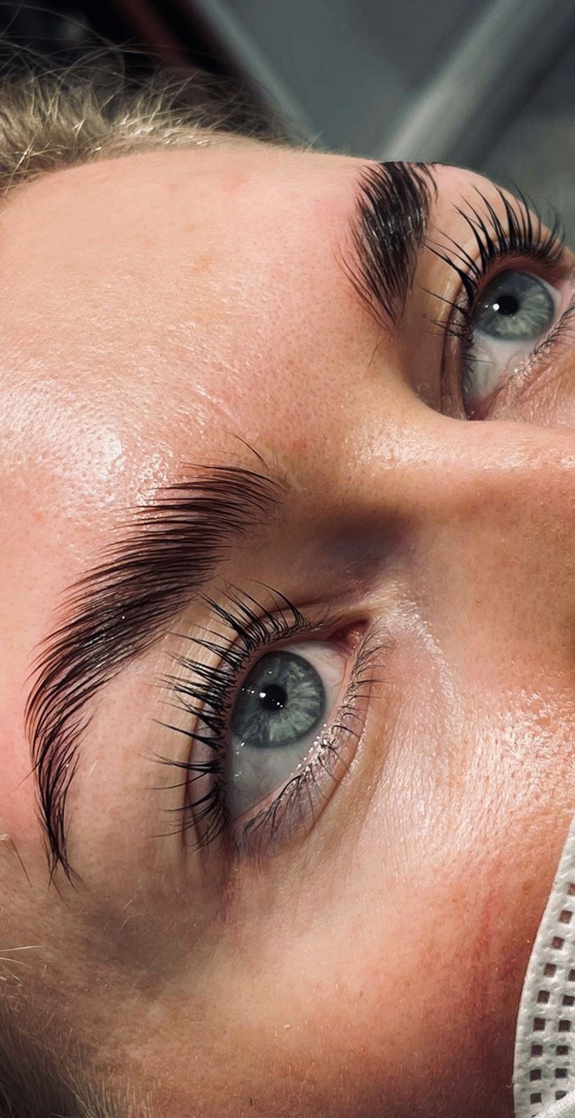 Eine Nahaufnahme des Gesichts einer Frau mit blauen Augen und langen Wimpern.