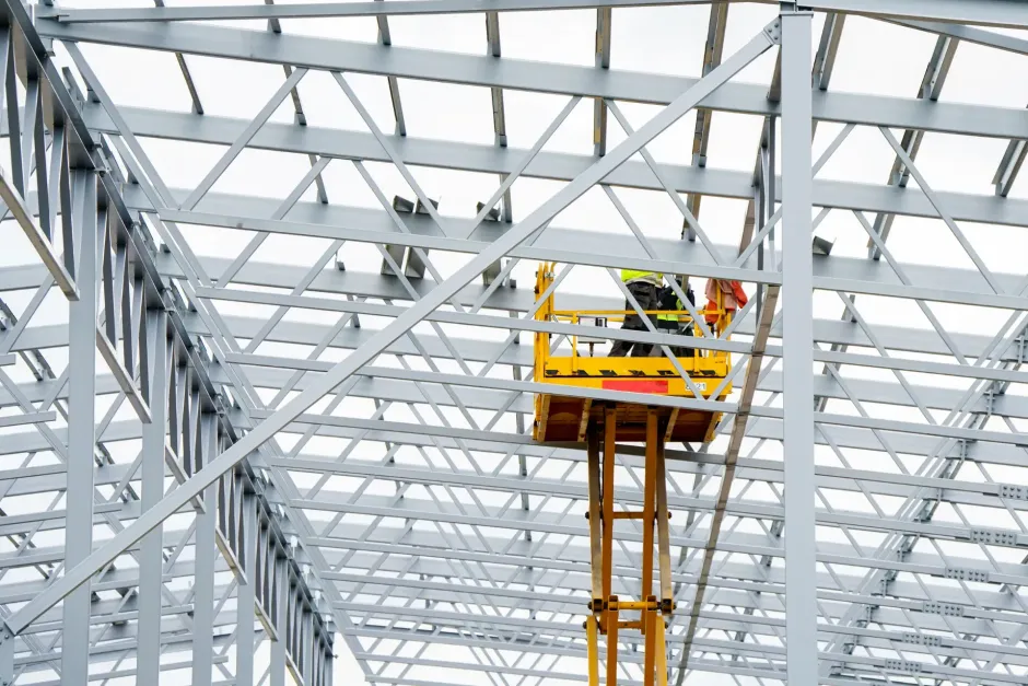 Un trabajador de la construcción está de pie en un ascensor en el techo de un edificio en construcción.