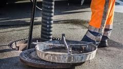 Ein Arbeiter öffnet einen Kanaldeckel.