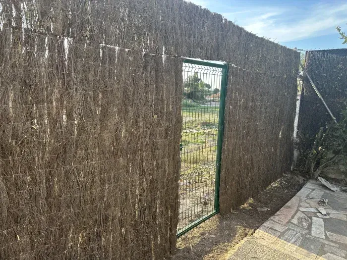 Una valla con una puerta verde en el medio.