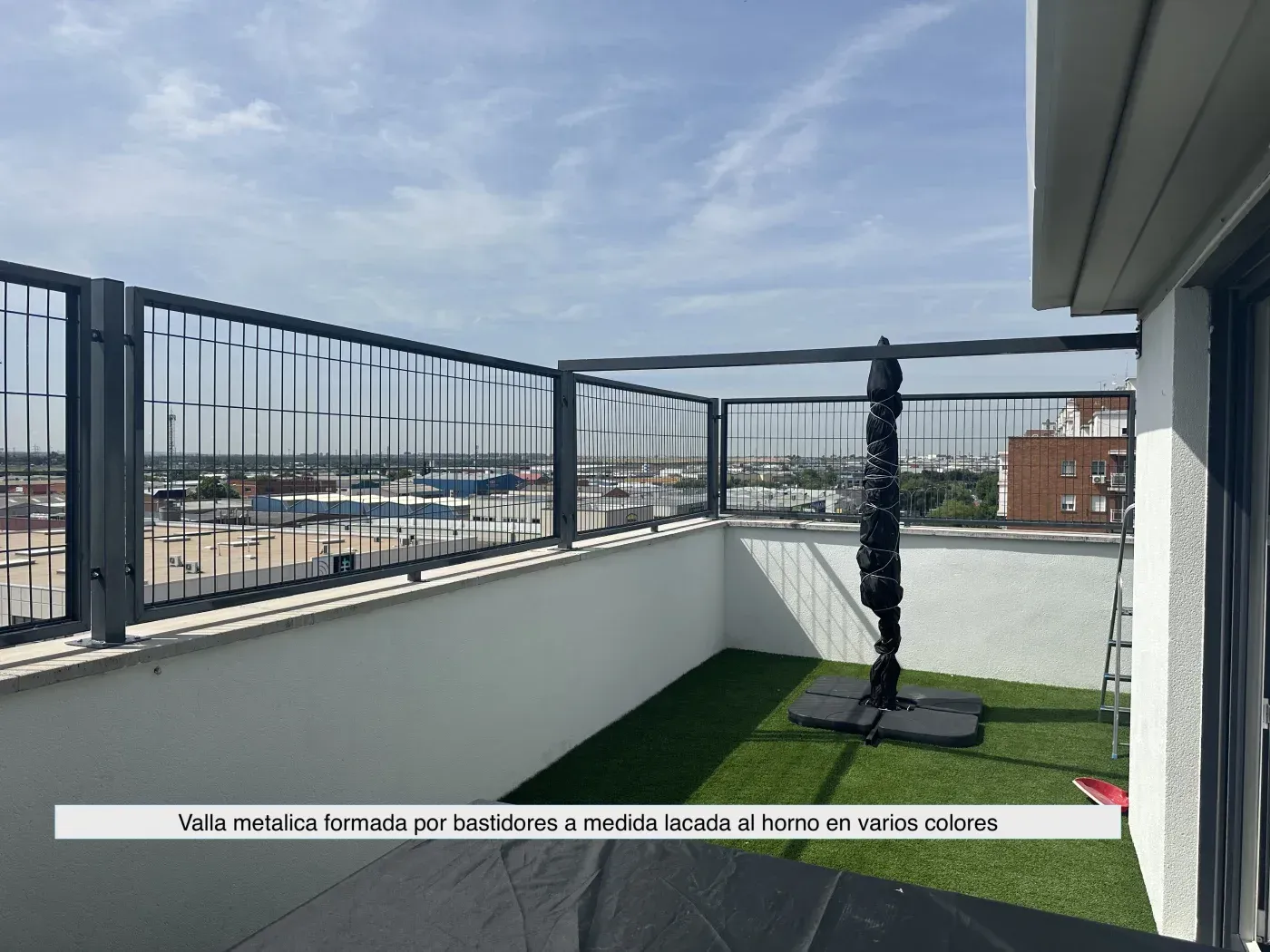 Un balcón con valla y vista a la ciudad.